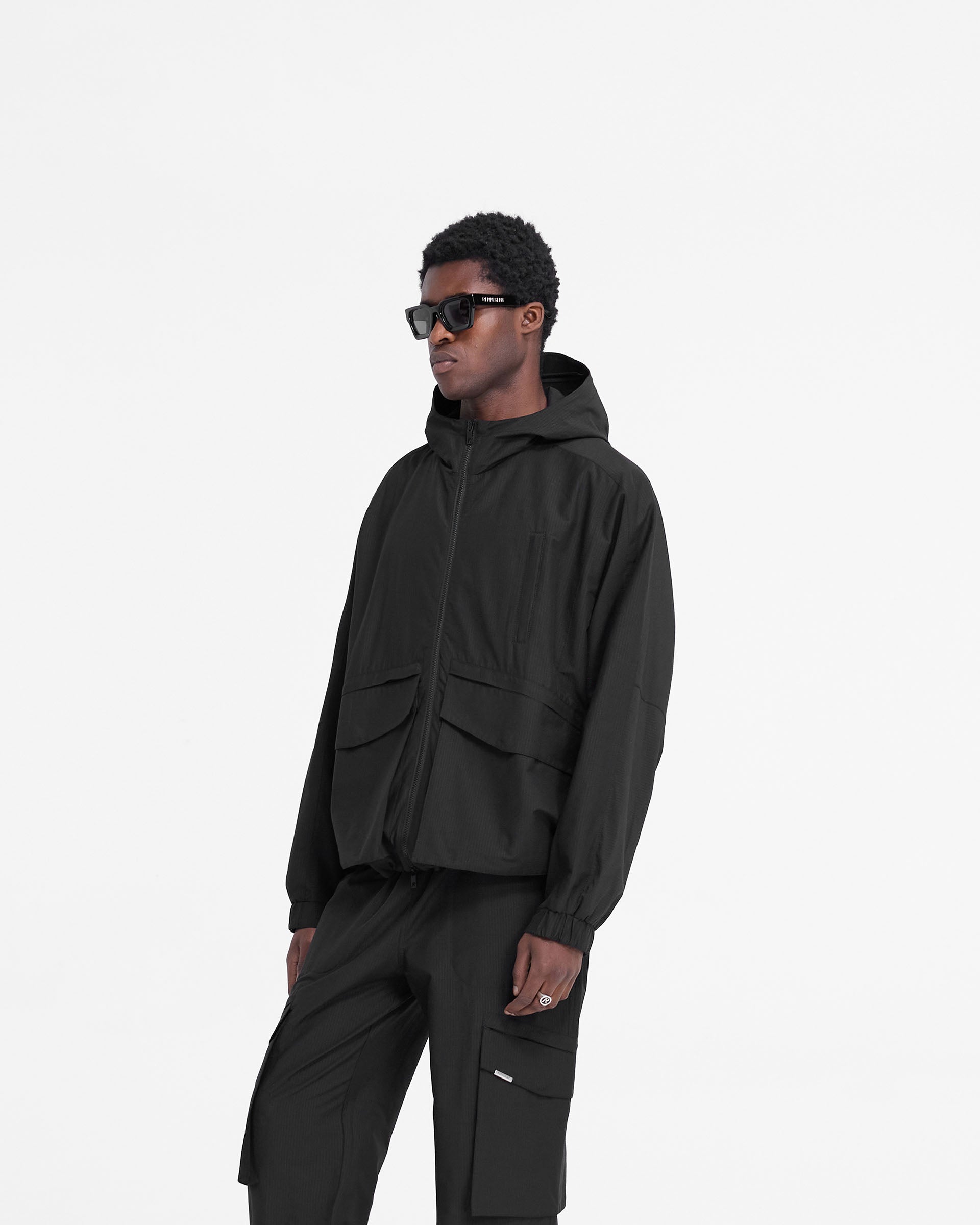 Back product image of a mens black jacket on a plain white background | Tech Cargo Jacket in Jet Black | Oversized jacket with tonal zippers and elasticated cuffs | FW24 Outerwear | Represent Clo