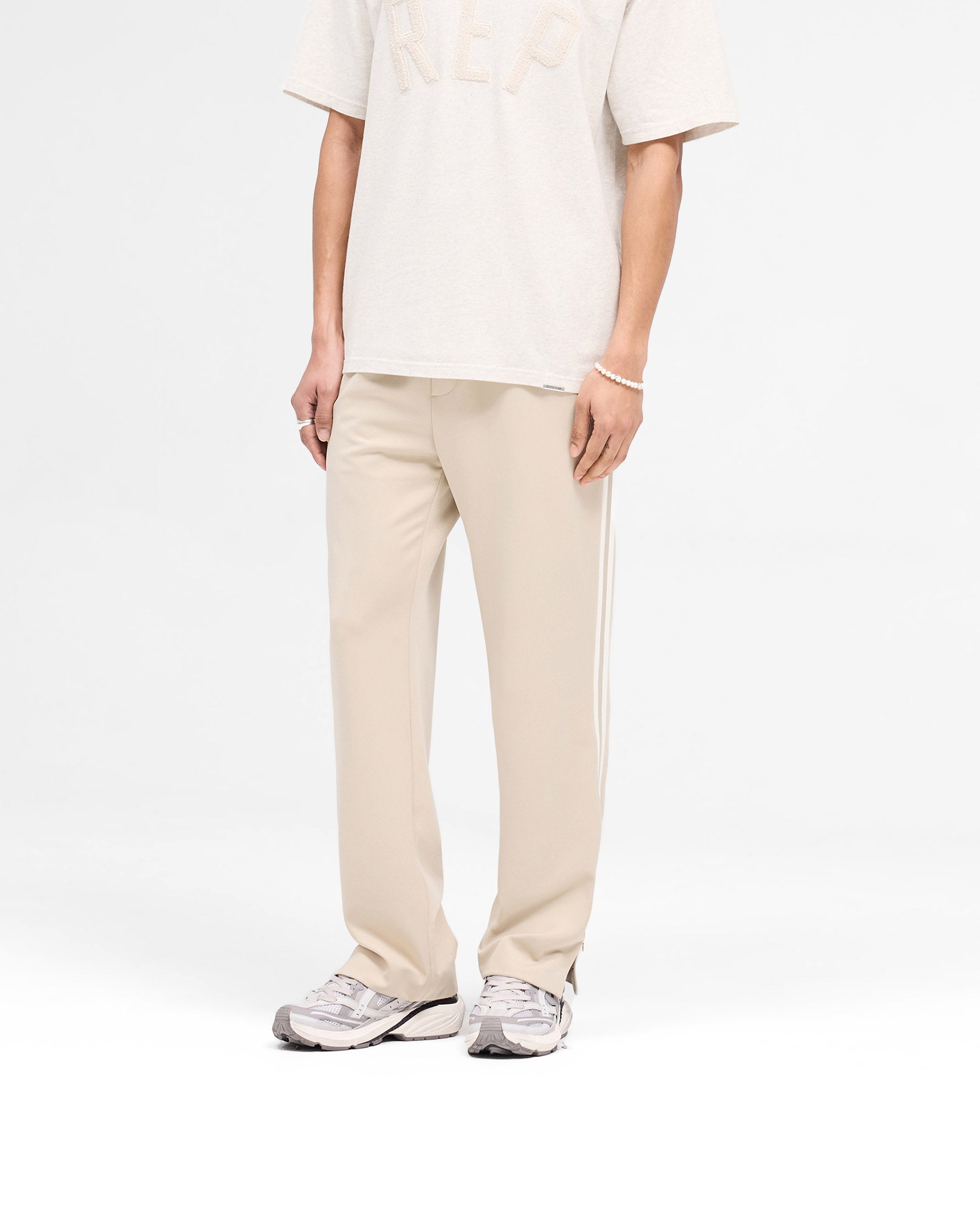 Back product image of mens stone pants on a plain white background | Tailored Track Pant in Stone | Pants with elasticated waistband and slash pockets | SS25 Pants | Represent Clo