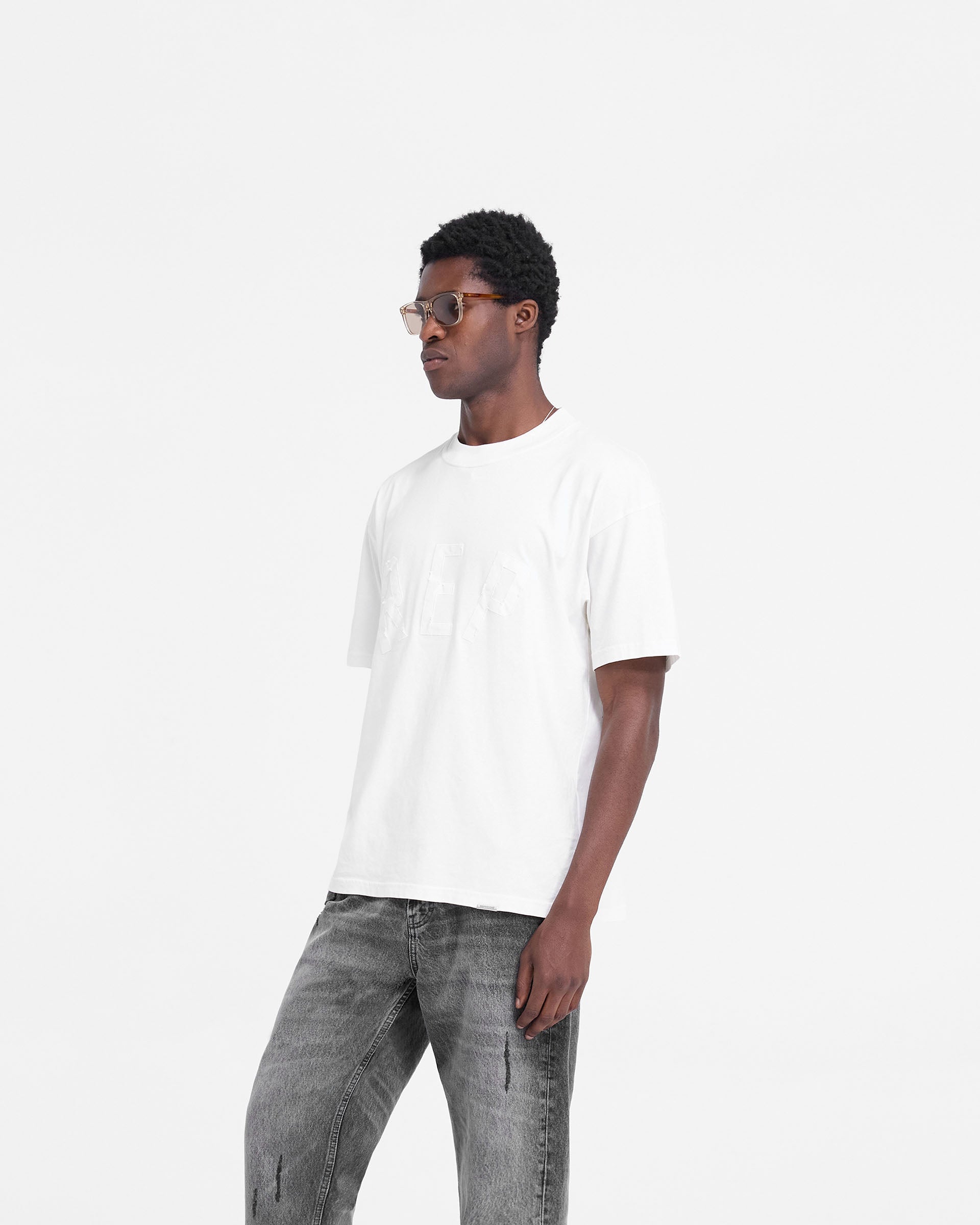 Back product image of a mens white t-shirt on a plain white background | Rep Applique T-Shirt in Flat White | Oversized t-shirt with distressed applique logo | FW24 T-Shirts | Represent Clo