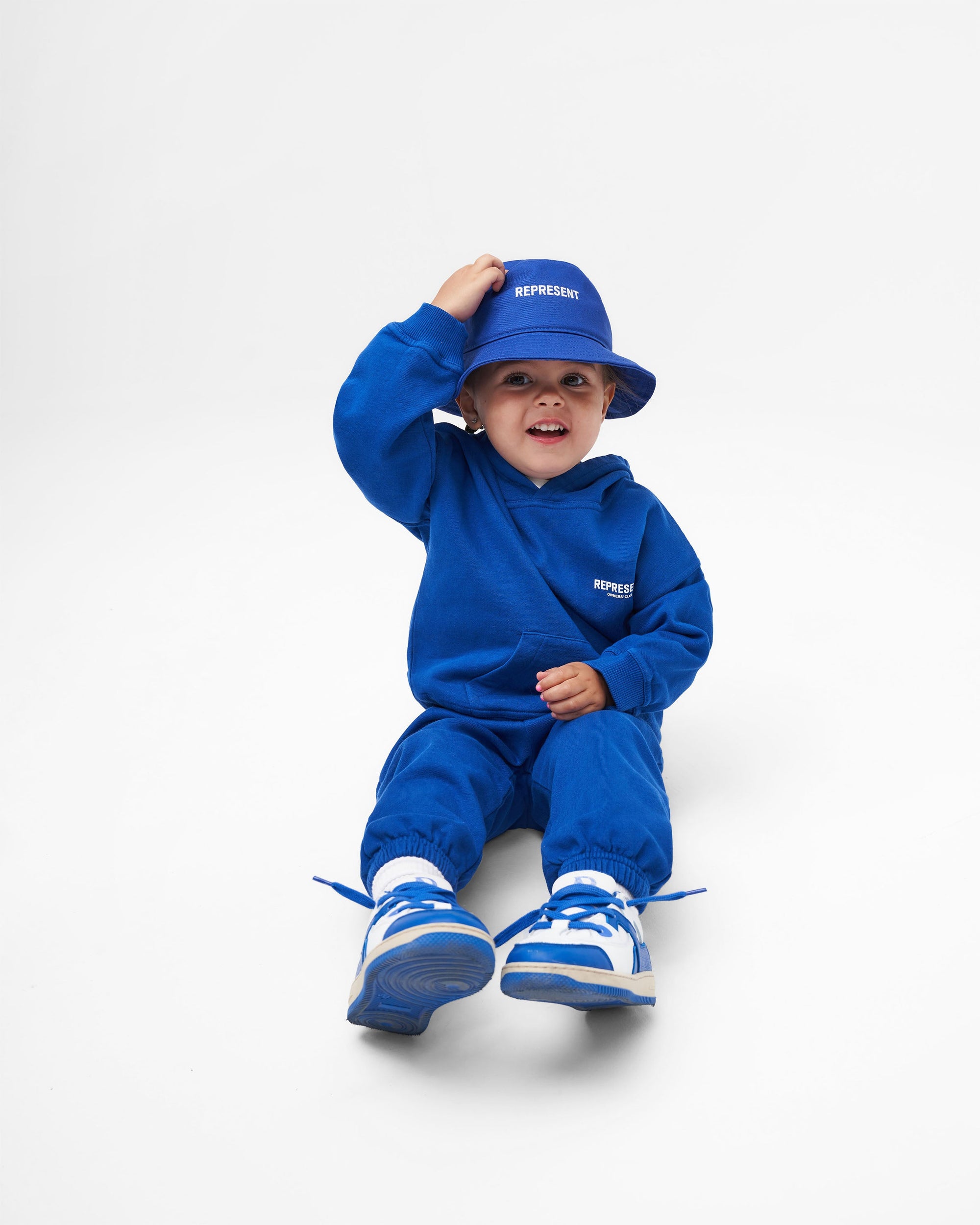 Back product image of kids blue sweatpants on a plain white background | Represent Mini Owners Club Sweatpants in Cobalt | Pants with elasticated waistband and cuffs | Owners Club Pants | Represent Clo