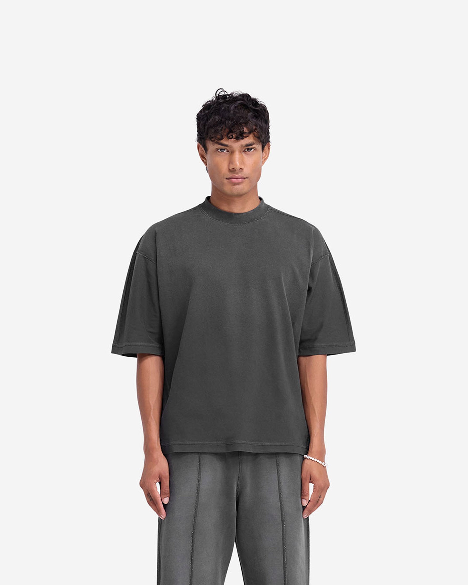 Man wearing an oversized black t-shirt with stepped hem on a plain white background | Stepped Hem T-Shirt in Stained Black | Oversized t-shirt with fade out wash and overlock seams | FW24 T-Shirts | Represent Clo