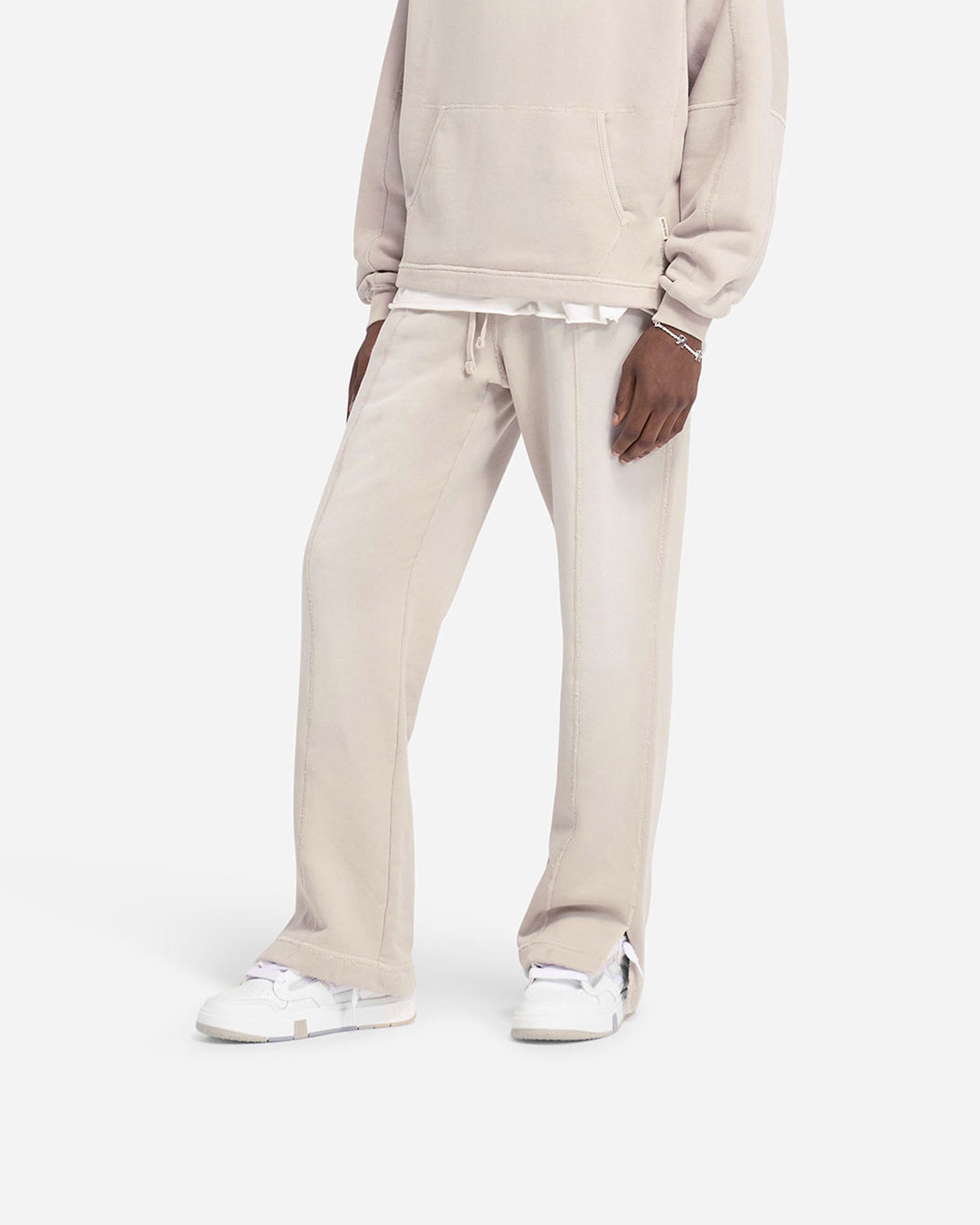 Man wearing oat wide leg sweatpants on a plain white background | Stepped Hem Sweatpants in Oat | Sweatpants with stepped hem and sun fade wash | FW24 Pants | Represent Clo