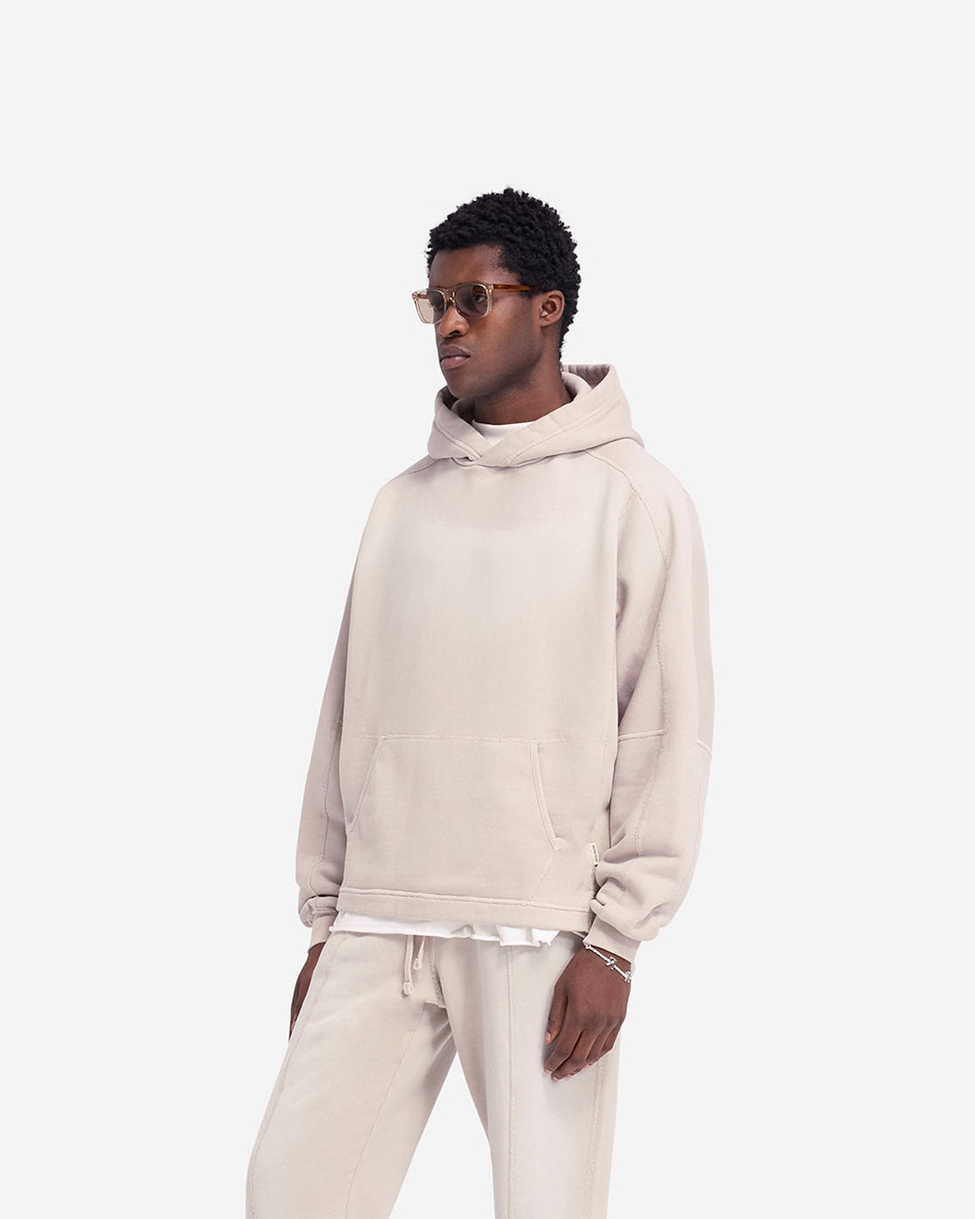 Man wearing an oversized oat hoodie on a plain white background | Stepped Hem Hoodie in Oat | Oversized hoodie with sun fade wash and stepped hem | FW24 Hoodies | Represent Clo