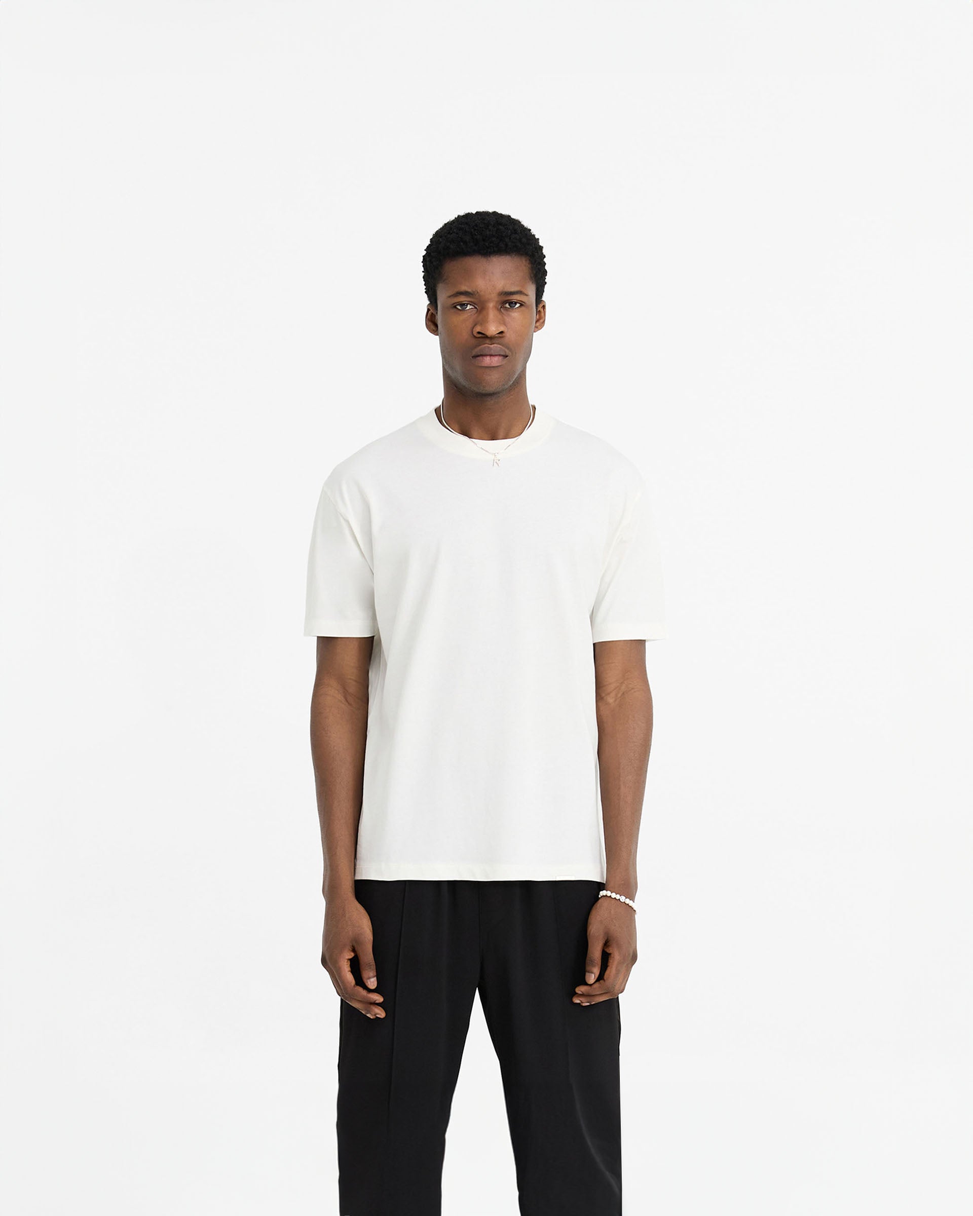 Man wearing a white t-shirt on a plain white background | Initial T-Shirt in Flat White | Slim fit t-shirt with embroidered initial and metal bar logo | Initial T-Shirts | Represent Clo