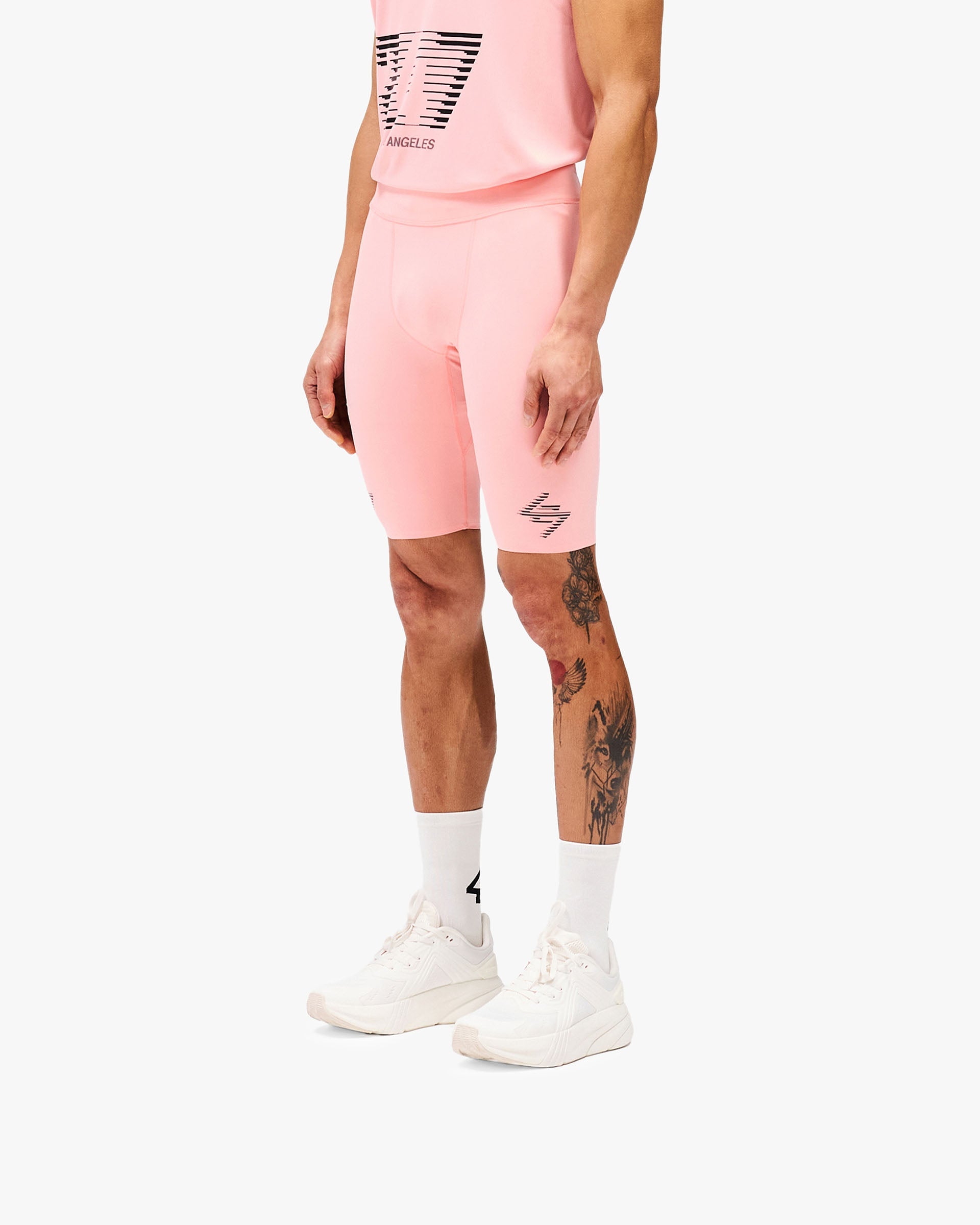 Man wearing pink compression shorts on a plain white background | 247 Los Angeles Half Tight in Pink | Performance shorts with towel loop and secure zip pocket | 247 Shorts | Represent Clo