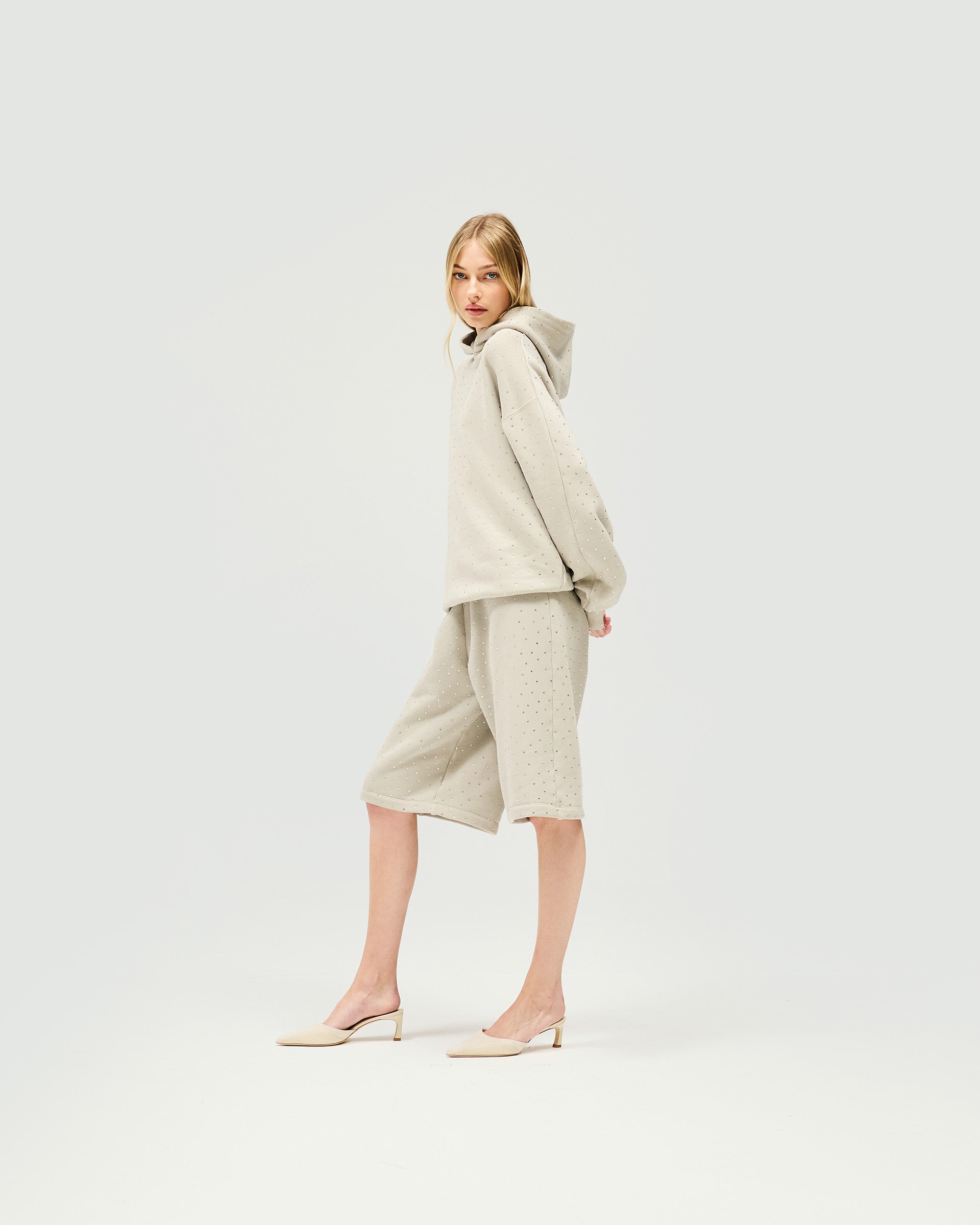Woman wearing mid rise grey leather shorts on a plain white background | Spark Shorts in Storm | Bermuda shorts with elasticated waist | SS25 Shorts | Represent Clo
