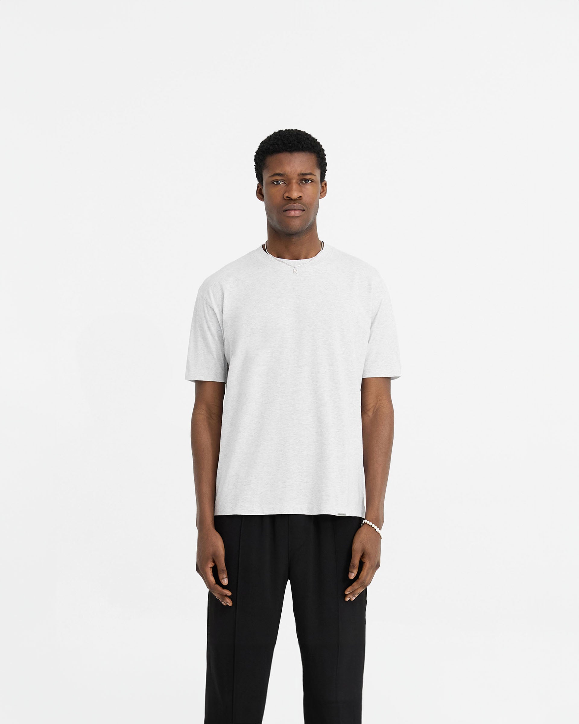 Man wearing a grey t-shirt on a plain white background | Initial T-Shirt in Ice Grey Marl | Regular fit t-shirt with shorter sleeves | Initial T-Shirts | Represent Clo