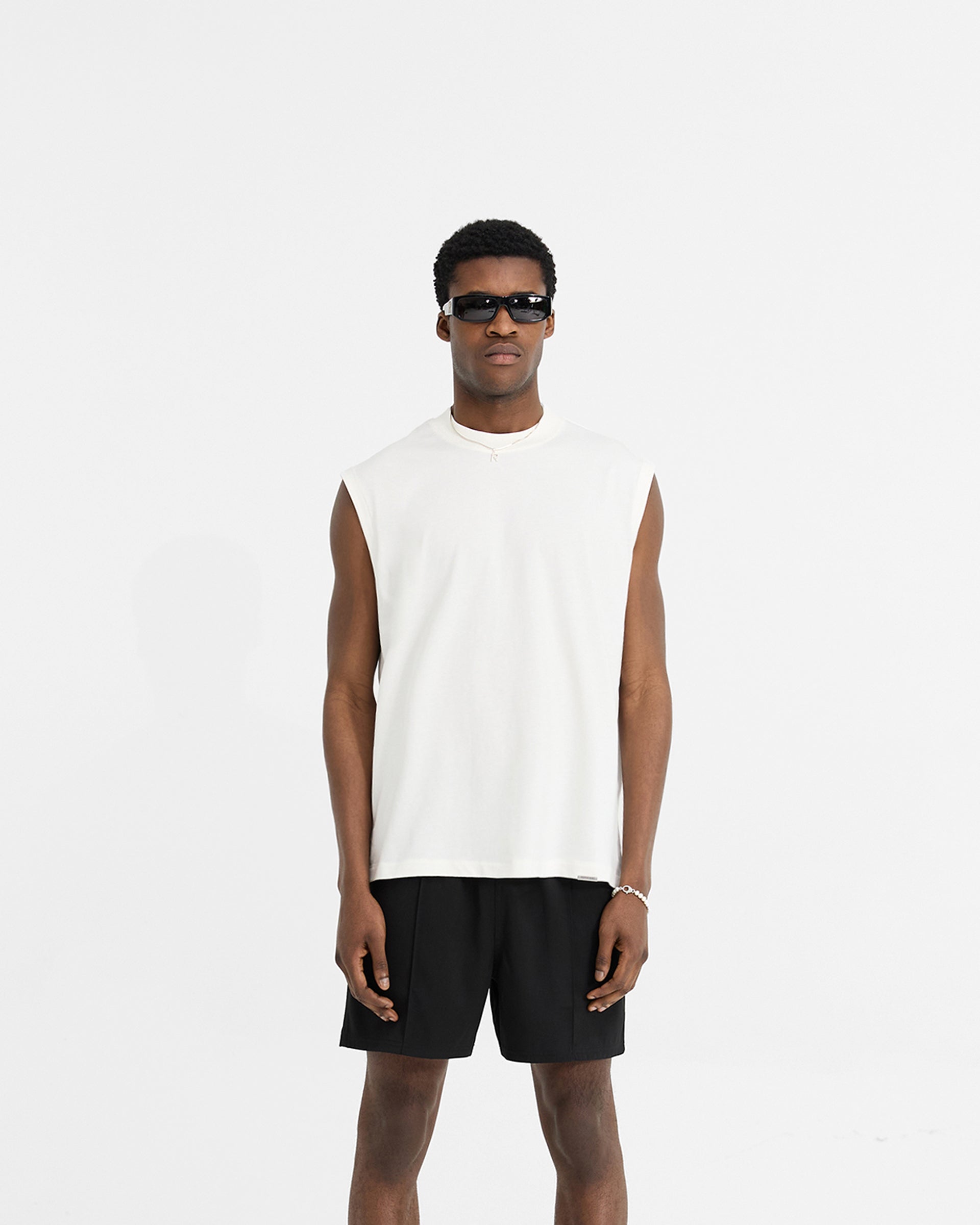 Man wearing a white oversized tank on a plain white background | Initial Boxy Tank in Flat White | Boxy cropped tank with embroidered details | Initial T-Shirts | Represent Clo