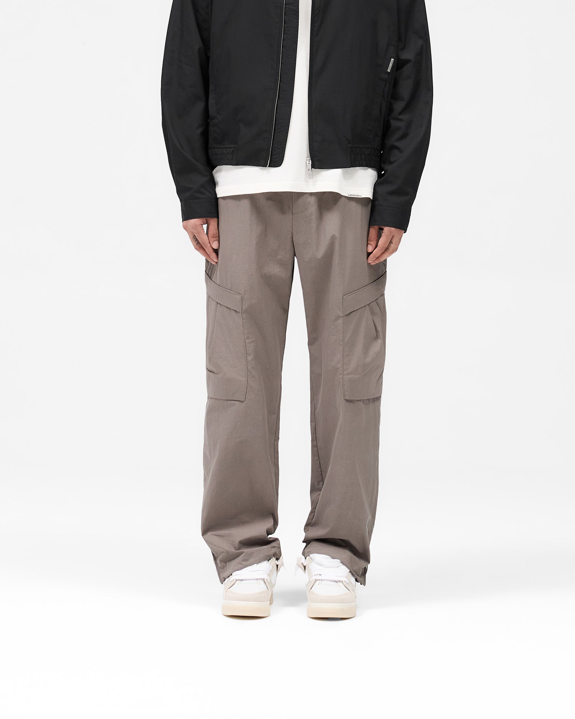 Man wearing grey cargo pants on a plain white background | Tech Cargo Pant in Mid Grey | Pants with pleated cargo pockets and adjustable fit | SS25 Pants | Represent Clo