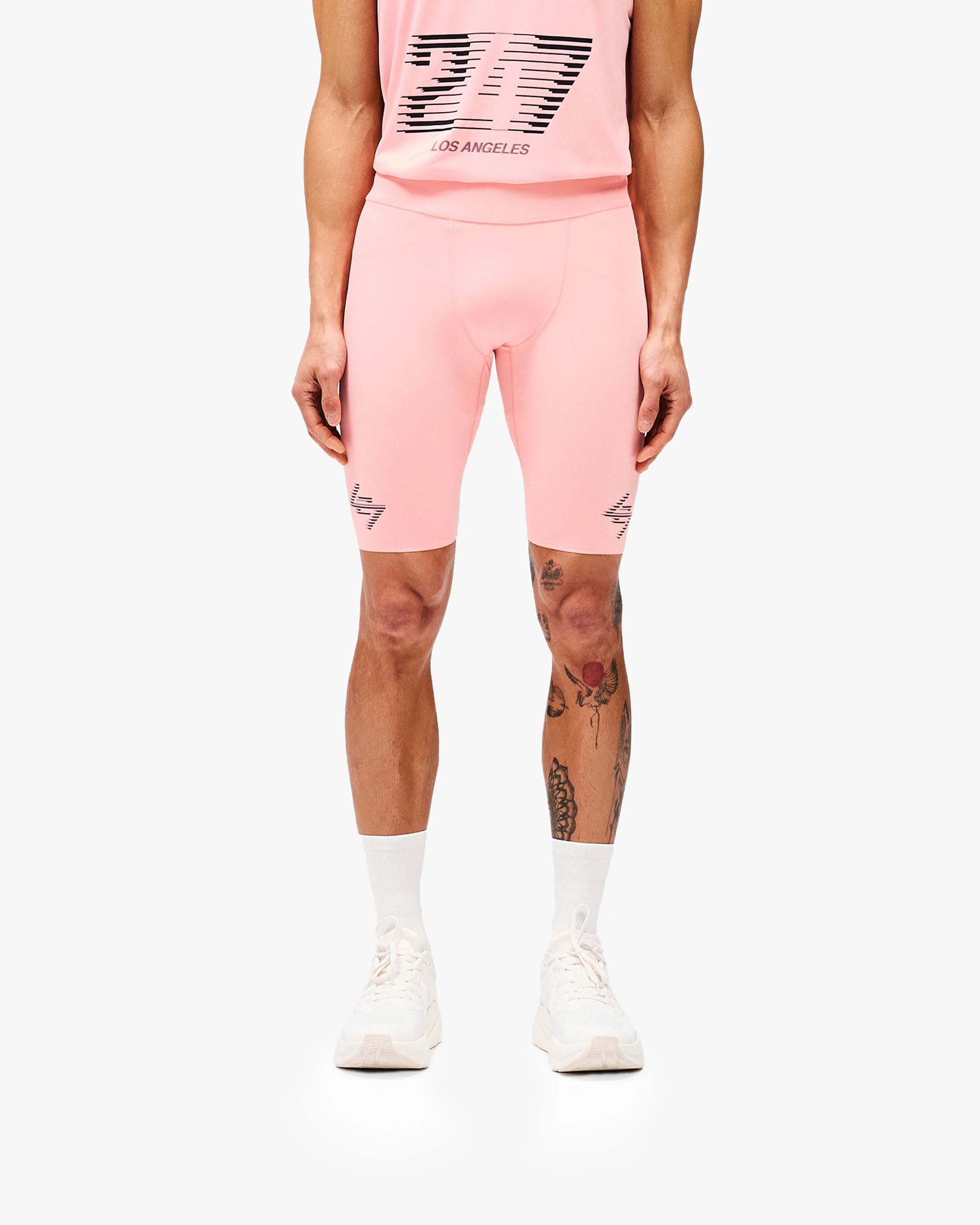 Man wearing pink half tights on a plain white background | 247 Los Angeles Half Tight in Pink | Performance compression shorts with towel loop and zip pocket | 247 Shorts | Represent Clo
