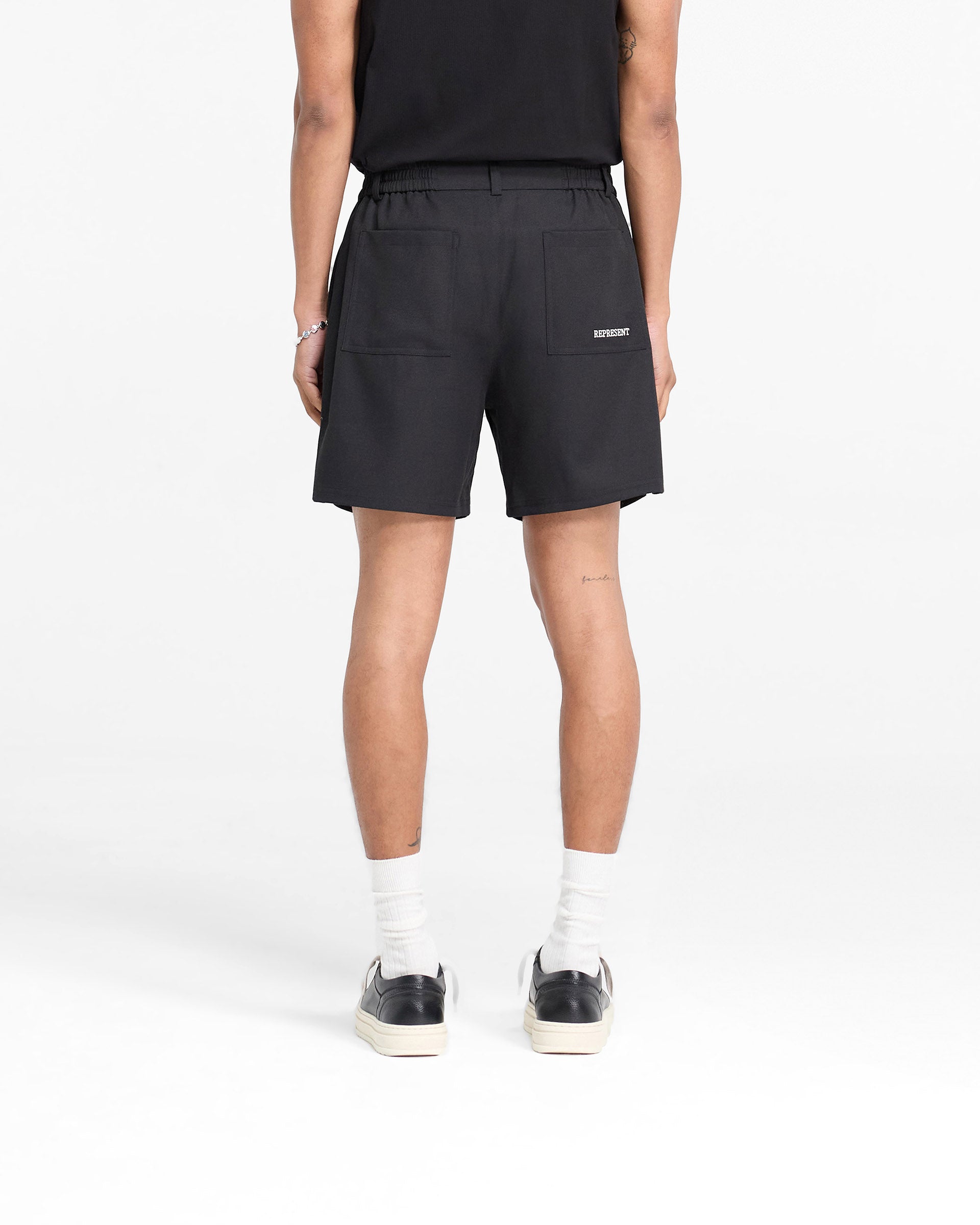 Man wearing black shorts on a plain white background | Logo Yacht Short in Black | Linen blend shorts with hybrid waistband | FW24 Shorts | Represent Clo