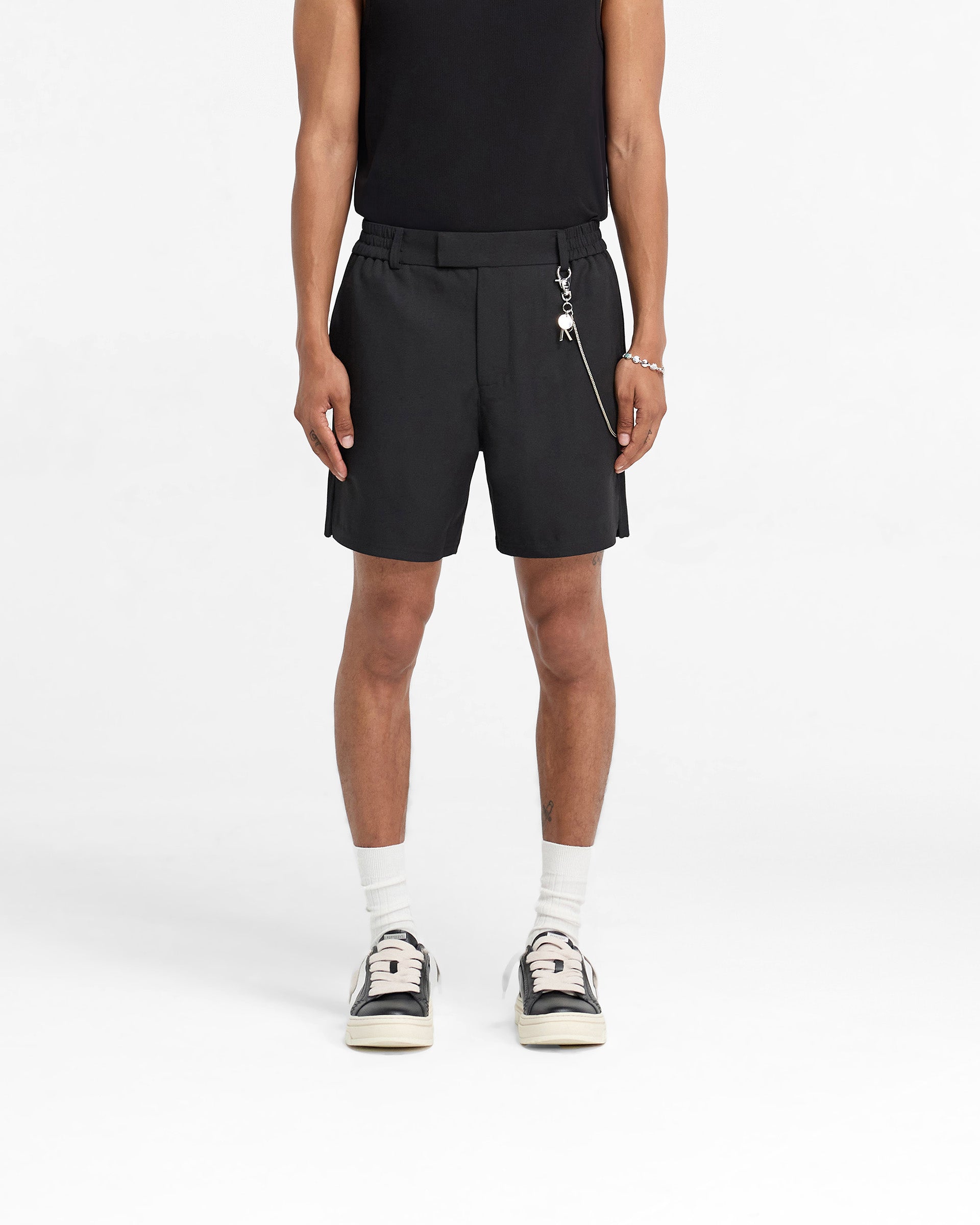 Man wearing black shorts on a plain white background | Logo Yacht Short in Black | Linen blend shorts with hybrid waistband and side split hem | FW24 Shorts | Represent Clo