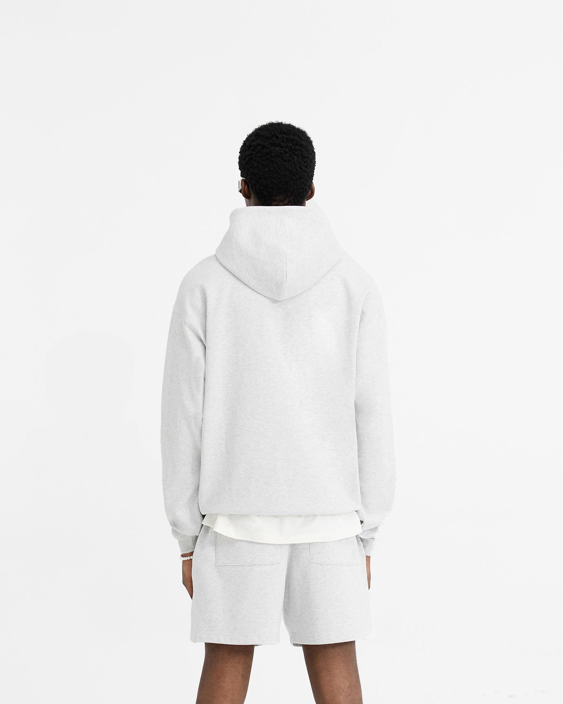 Man wearing a grey hoodie on a plain white background | Initial Oversized Hoodie in Ice Grey Marl | Heavyweight jersey cotton with kangaroo pocket | Initial Hoodies | Represent Clo