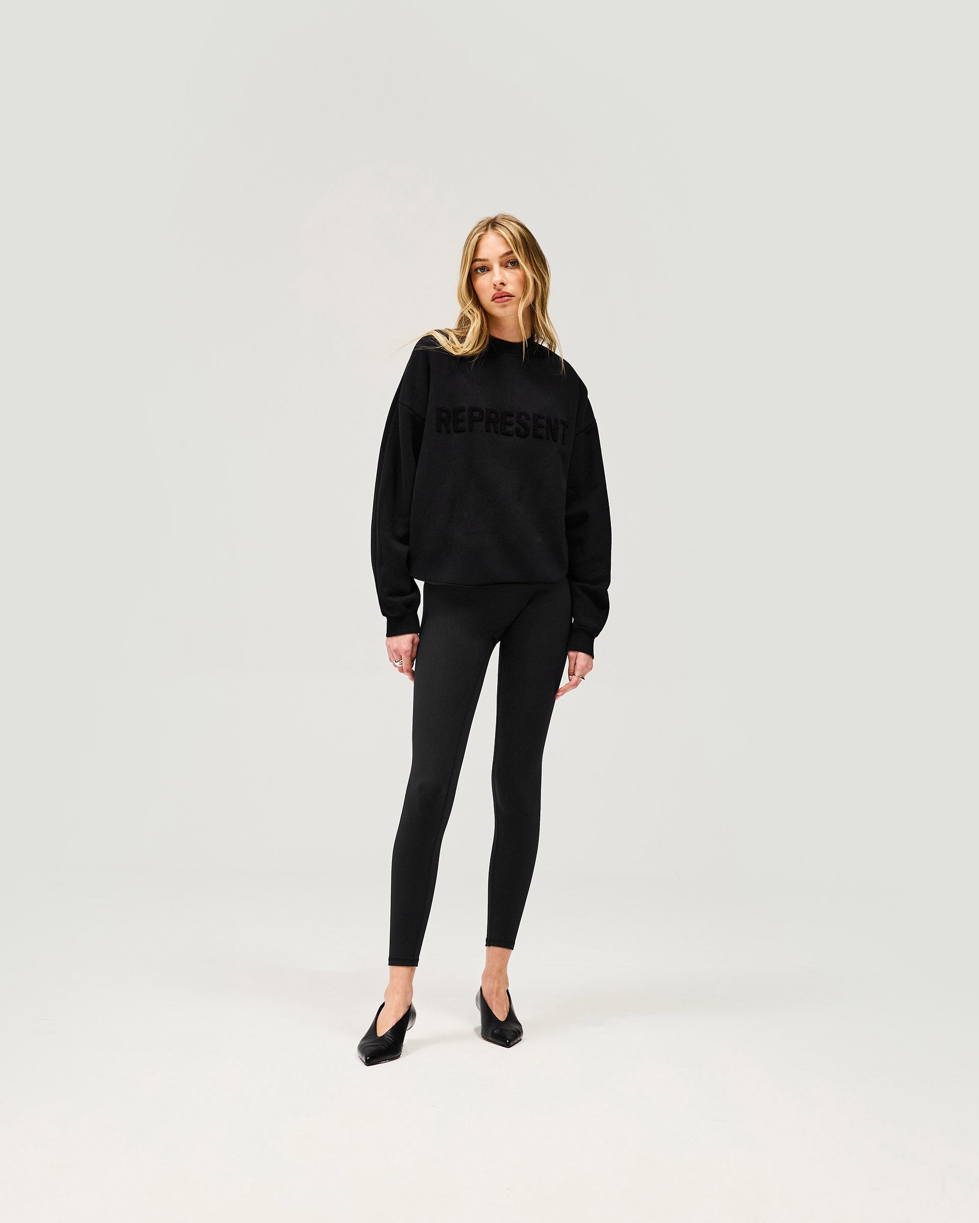 Woman wearing a black sweater on a plain white background | Owners Club Sweater in Jet Black | Relaxed fit sweater in soft brushed cotton fleece | Womens Owners Club Sweaters | Represent Clo