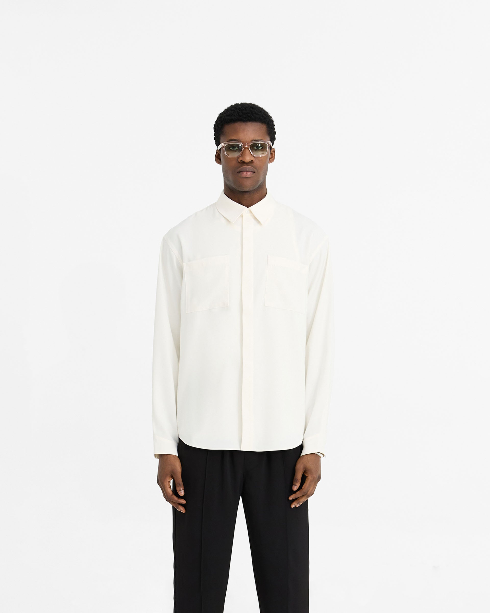 Man wearing a white shirt on a plain white background | Initial Shirt in Flat White | Drapey fabric oversized shirt with chest pockets | Initial Shirts | Represent Clo