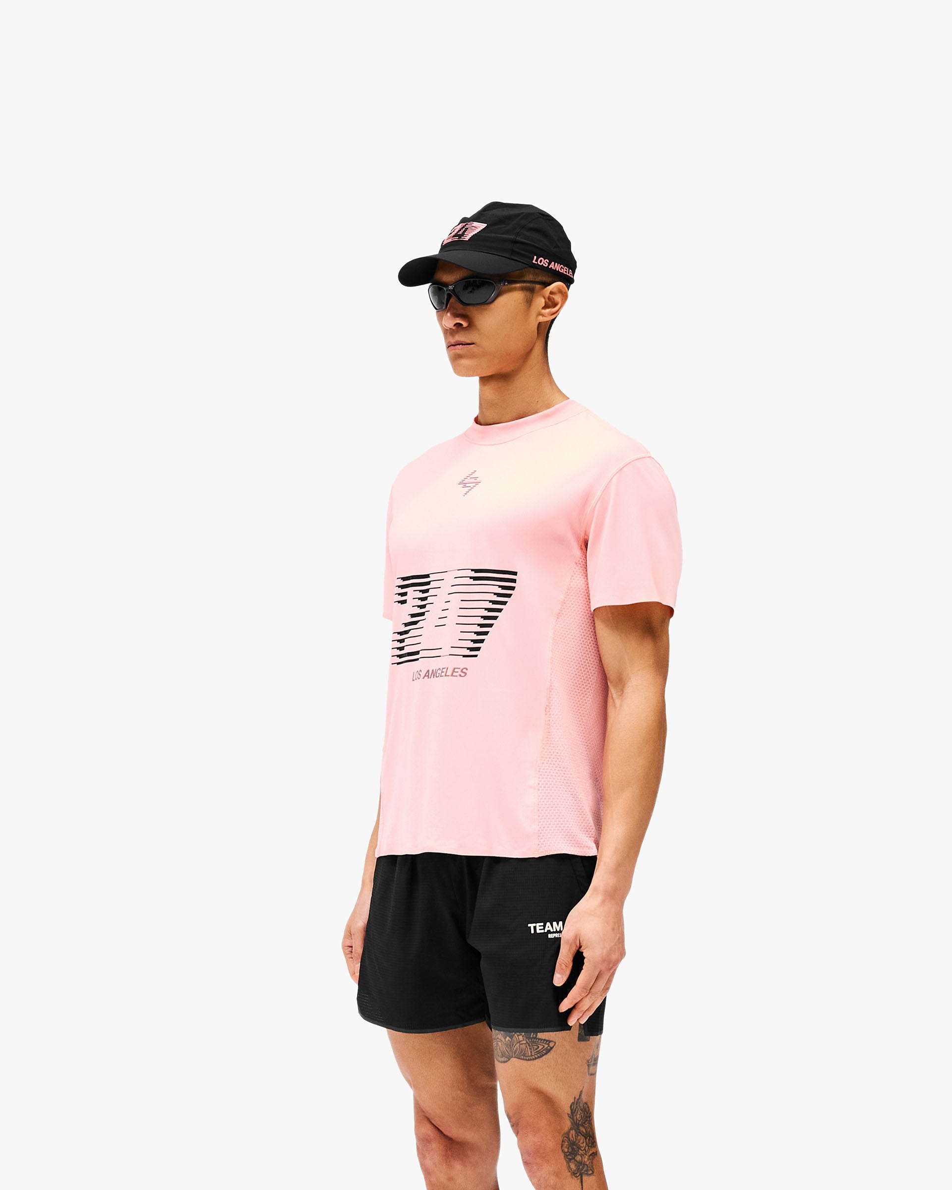 Man wearing a pink t-shirt on a plain white background | 247 Los Angeles T-Shirt in Pink | Lightweight t-shirt with sweat-wicking fabric and ergonomic fit | 247 T-Shirts | Represent Clo