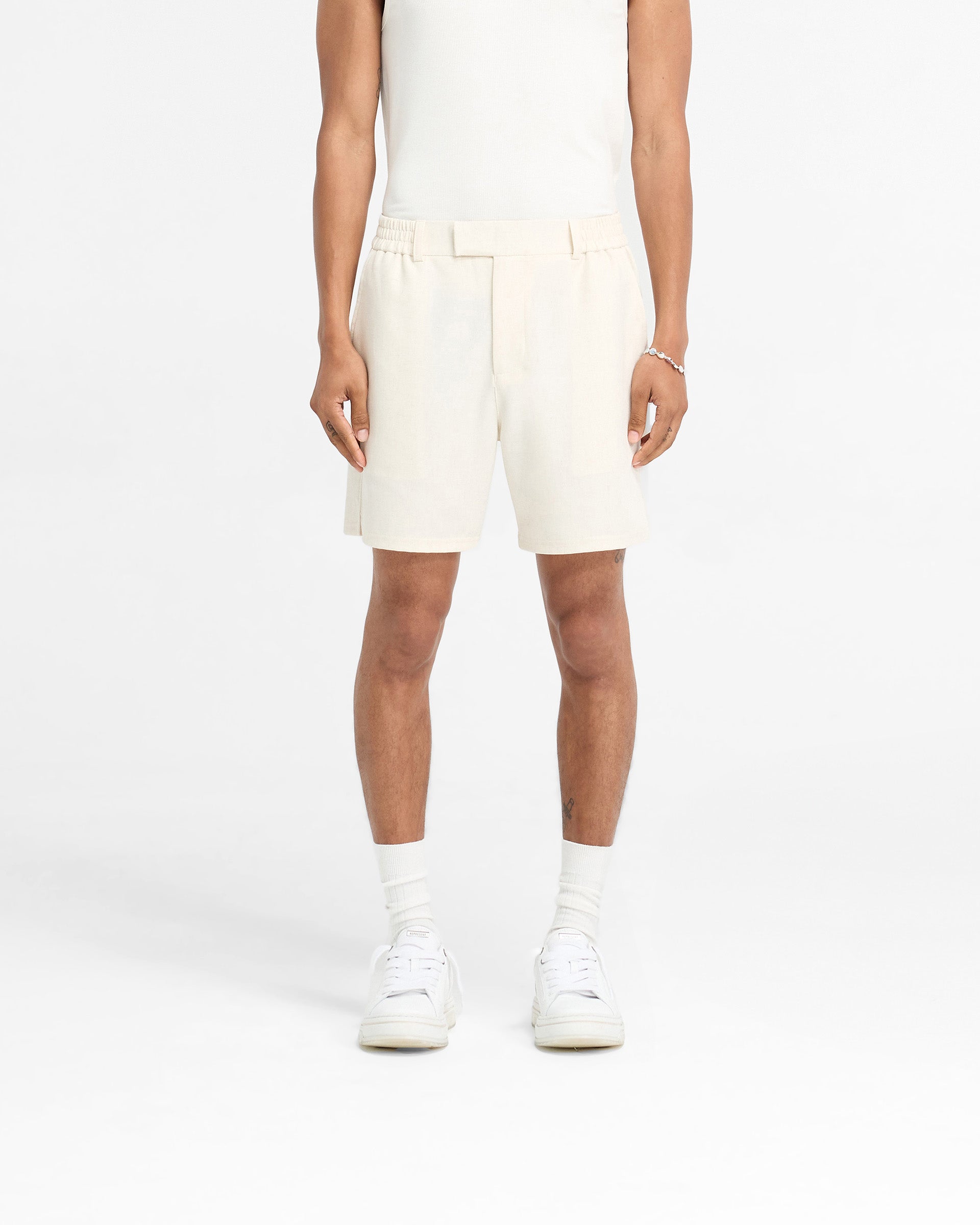 Man wearing antique white shorts on a plain white background | Logo Yacht Short in Antique White | Shorts with hybrid waistband and side splits | FW24 Shorts | Represent Clo
