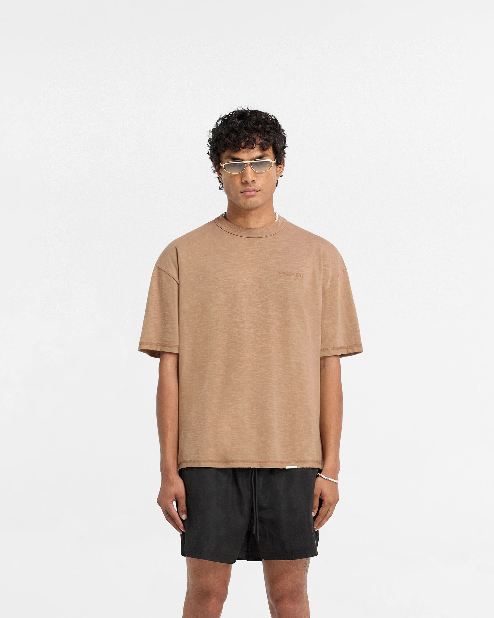 Man wearing a walnut brown t-shirt on a plain white background | Slub T-Shirt in Walnut | Oversized t-shirt with tonal embroidered branding | FW24 T-Shirts | Represent Clo