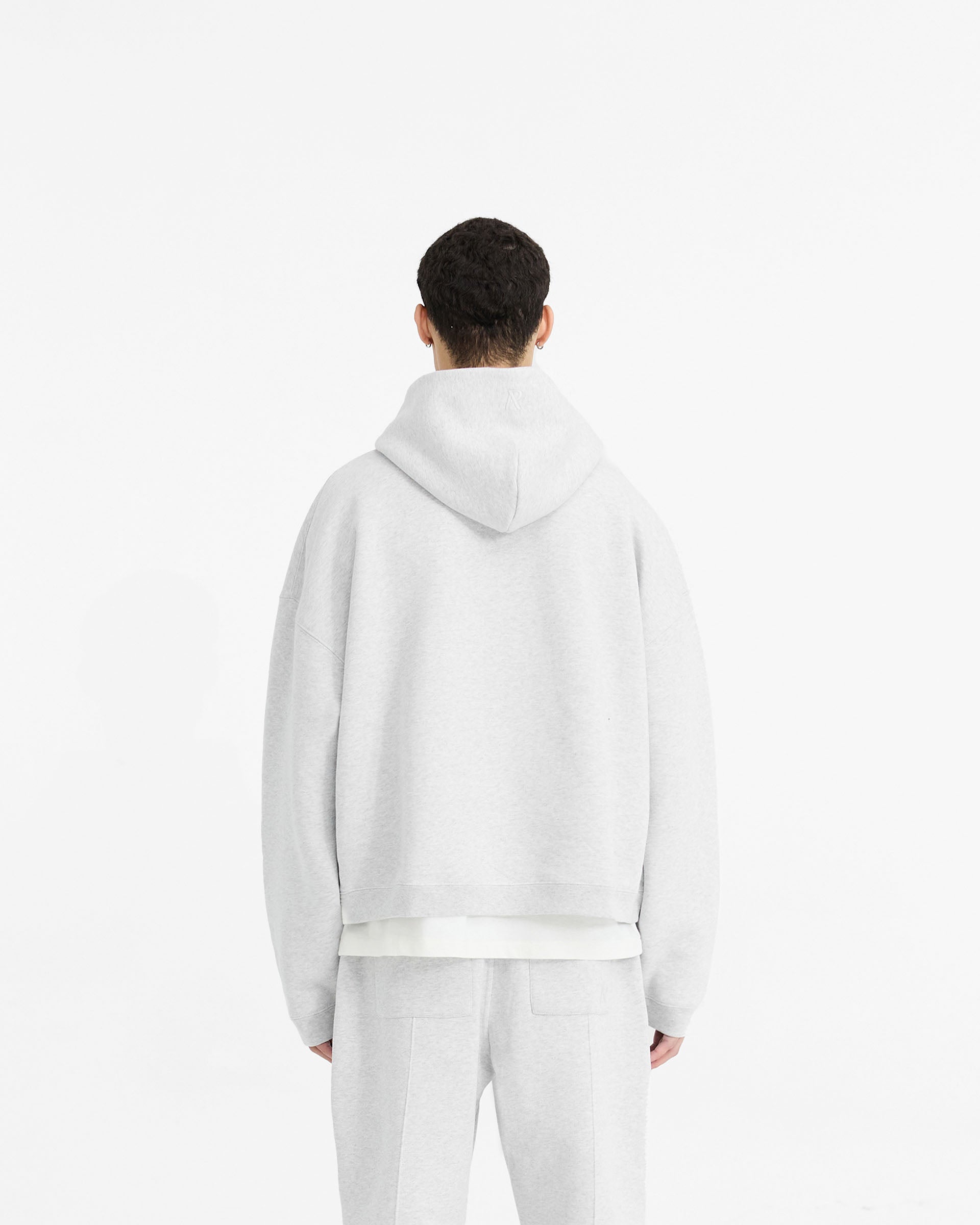 Man wearing an oversized grey hoodie on a plain white background | Initial Boxy Hoodie in Ice Grey Marl | Boxy fit cropped hoodie with ribbed cuffs | Initial Hoodies | Represent Clo