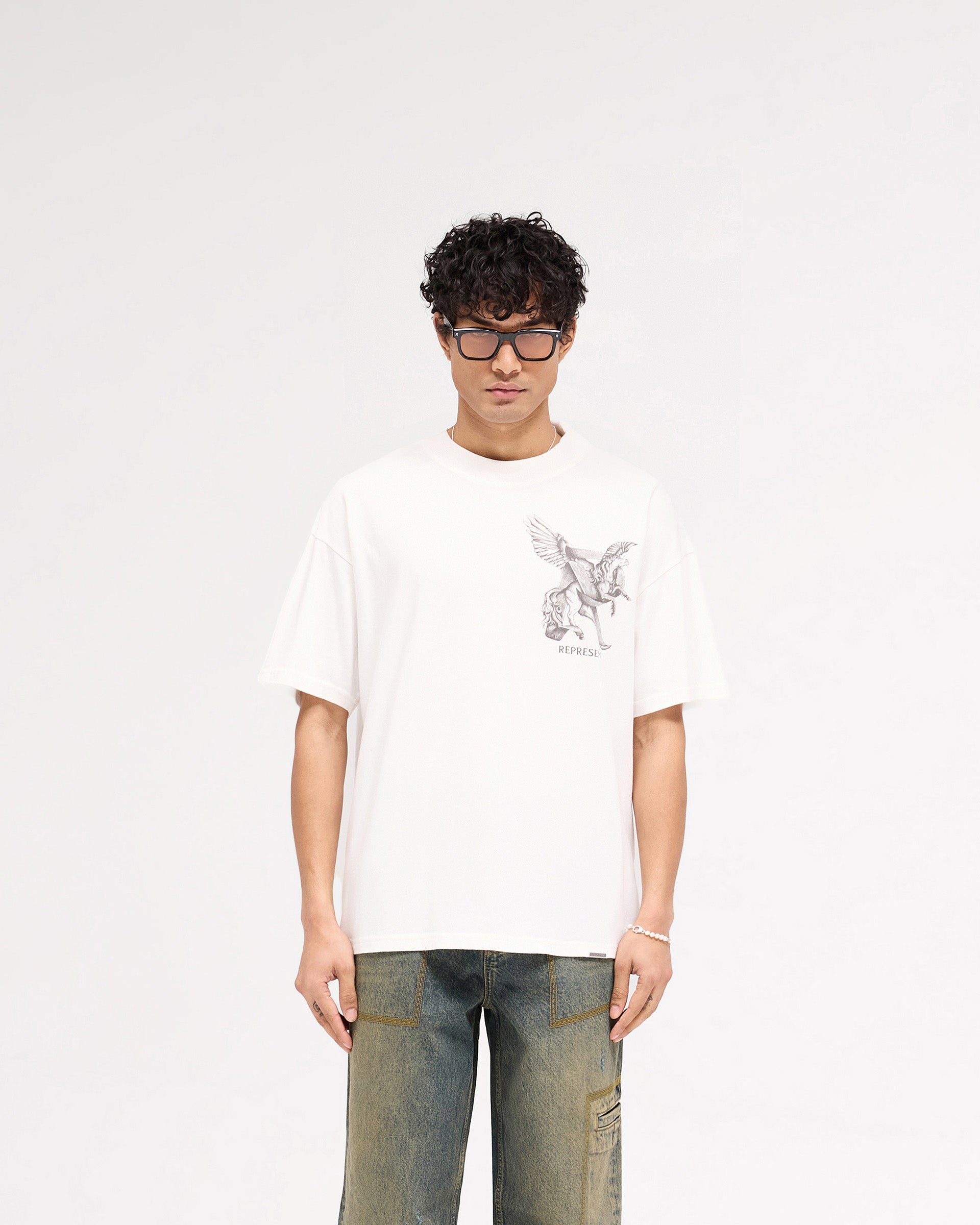 Man wearing a white t-shirt with graphic on a plain white background | Elegance In Motion T-Shirt in Flat White | Slightly oversized fit t-shirt | SS25 T-Shirts | Represent Clo