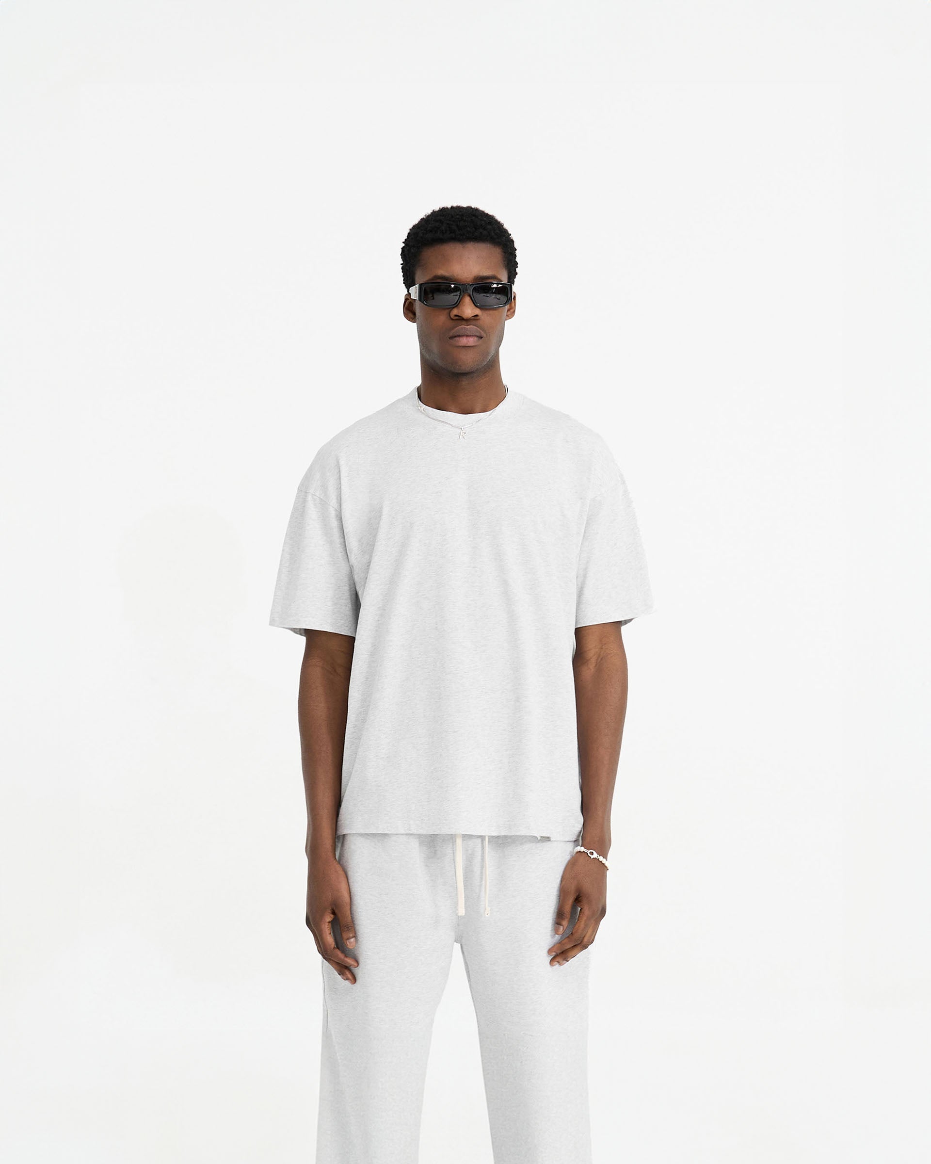 Man wearing a grey oversized t-shirt on a plain white background | Initial Oversized T-Shirt in Ice Grey Marl | T-shirt with embroidered back neck Initial | Initial T-Shirts | Represent Clo