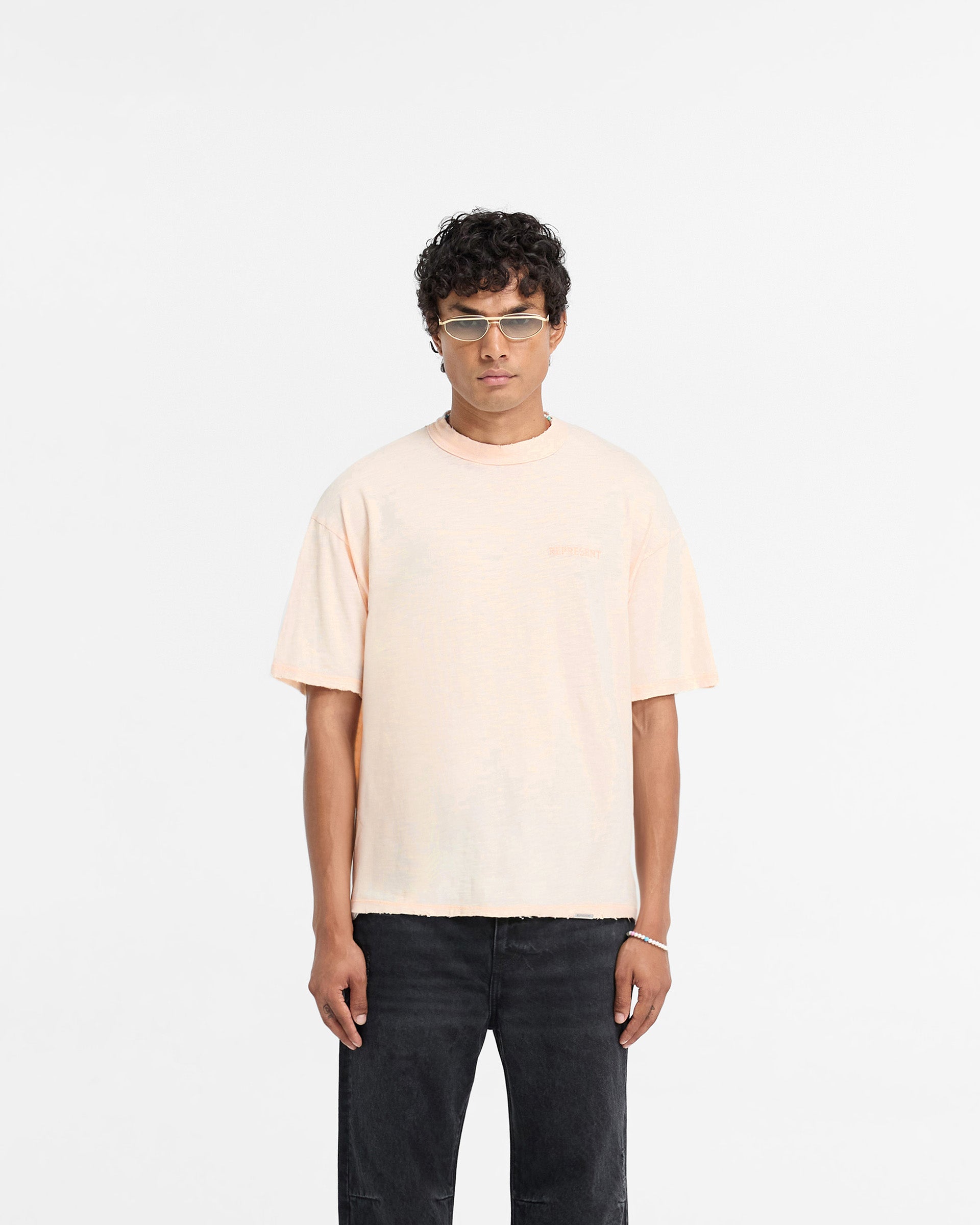 Man wearing a washed coral t-shirt on a plain white background | Slub T-Shirt in Washed Coral | Oversized fit cotton t-shirt with tonal embroidery | FW24 T-Shirts | Represent Clo
