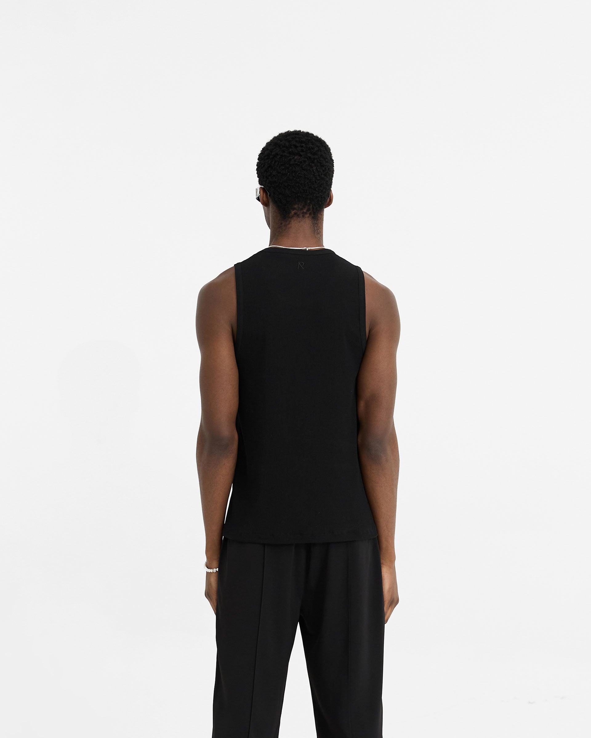 Man wearing a black rib vest on a plain white background | Initial Rib Vest in Black | Lightweight regular fit vest with neck and armhole binding | Initial T-Shirts | Represent Clo