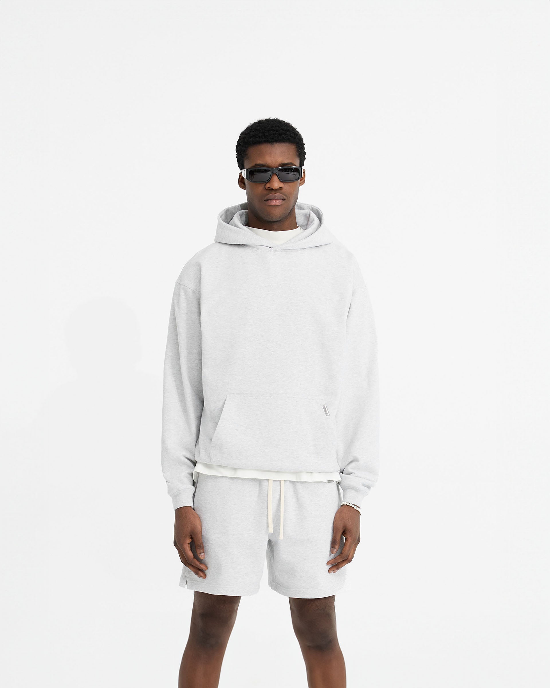Man wearing an oversized grey hoodie on a plain white background | Initial Oversized Hoodie in Ice Grey Marl | Heavyweight loopback jersey hoodie with kangaroo pocket | Initial Hoodies | Represent Clo