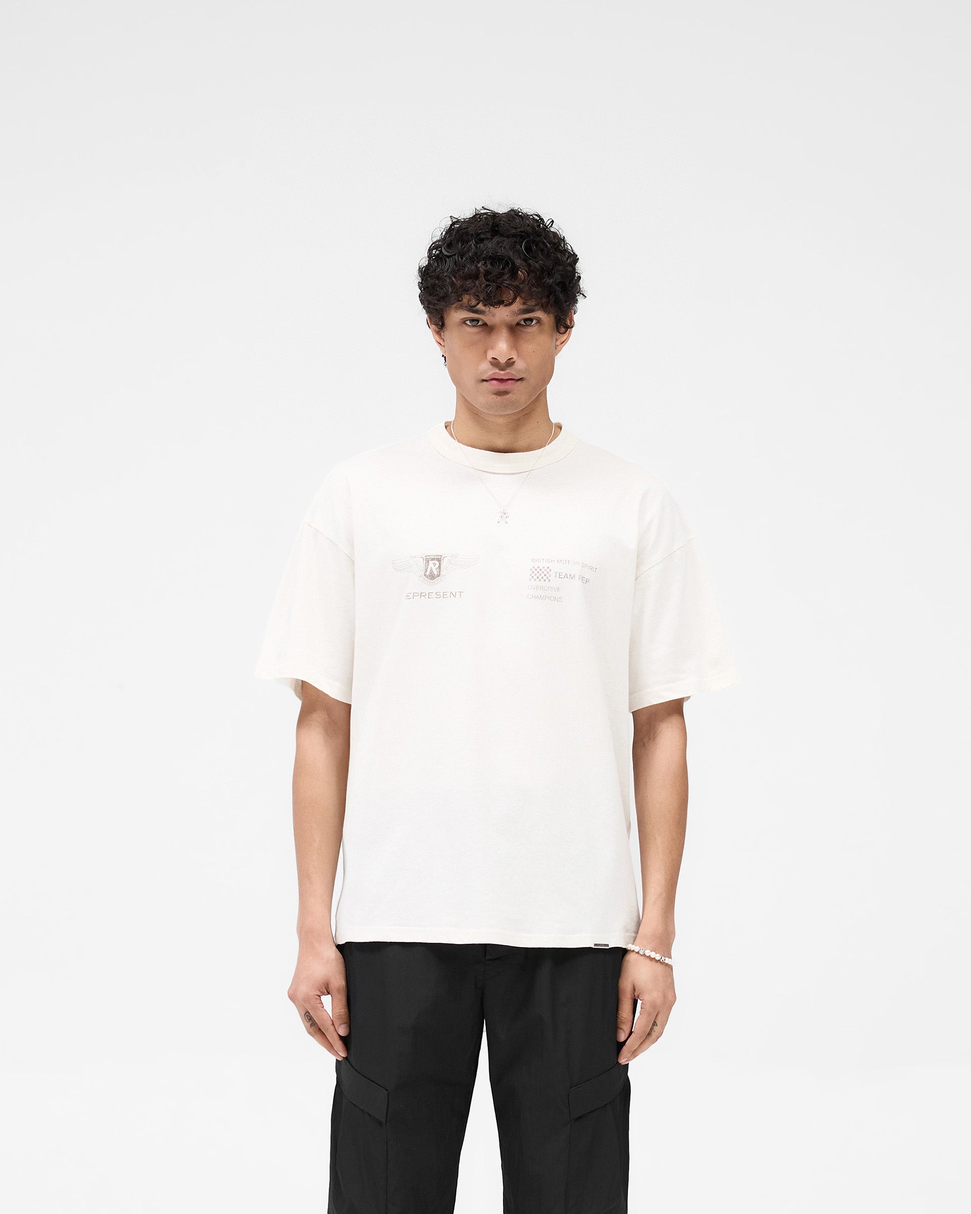 Man wearing an oversized white t-shirt on a plain white background | Team Rep T-Shirt in Flat White | Slub jersey oversized t-shirt with bound neckline | SS25 T-Shirts | Represent Clo