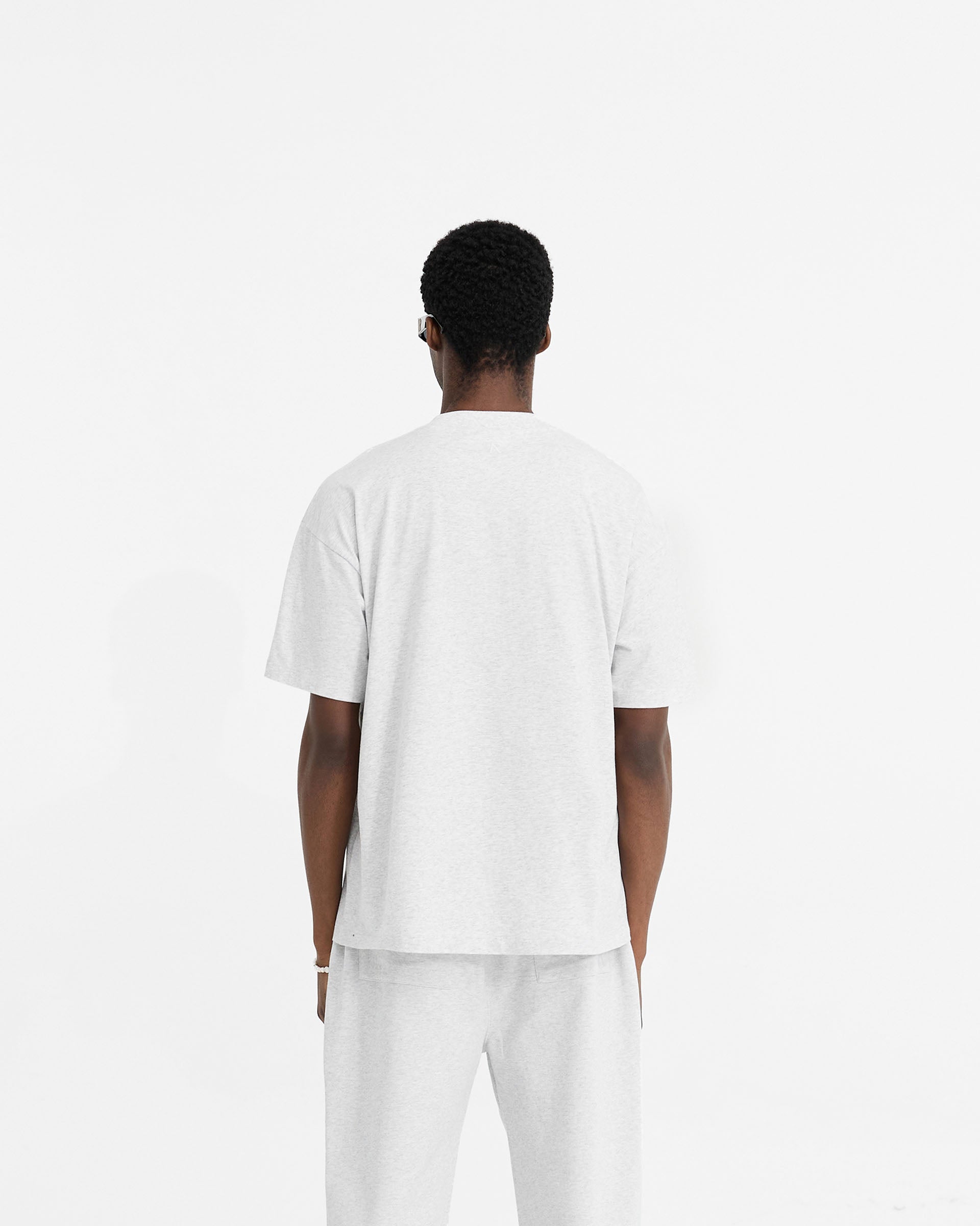 Man wearing a grey oversized t-shirt on a plain white background | Initial Oversized T-Shirt in Ice Grey Marl | Cotton t-shirt with embroidered details | Initial T-Shirts | Represent Clo