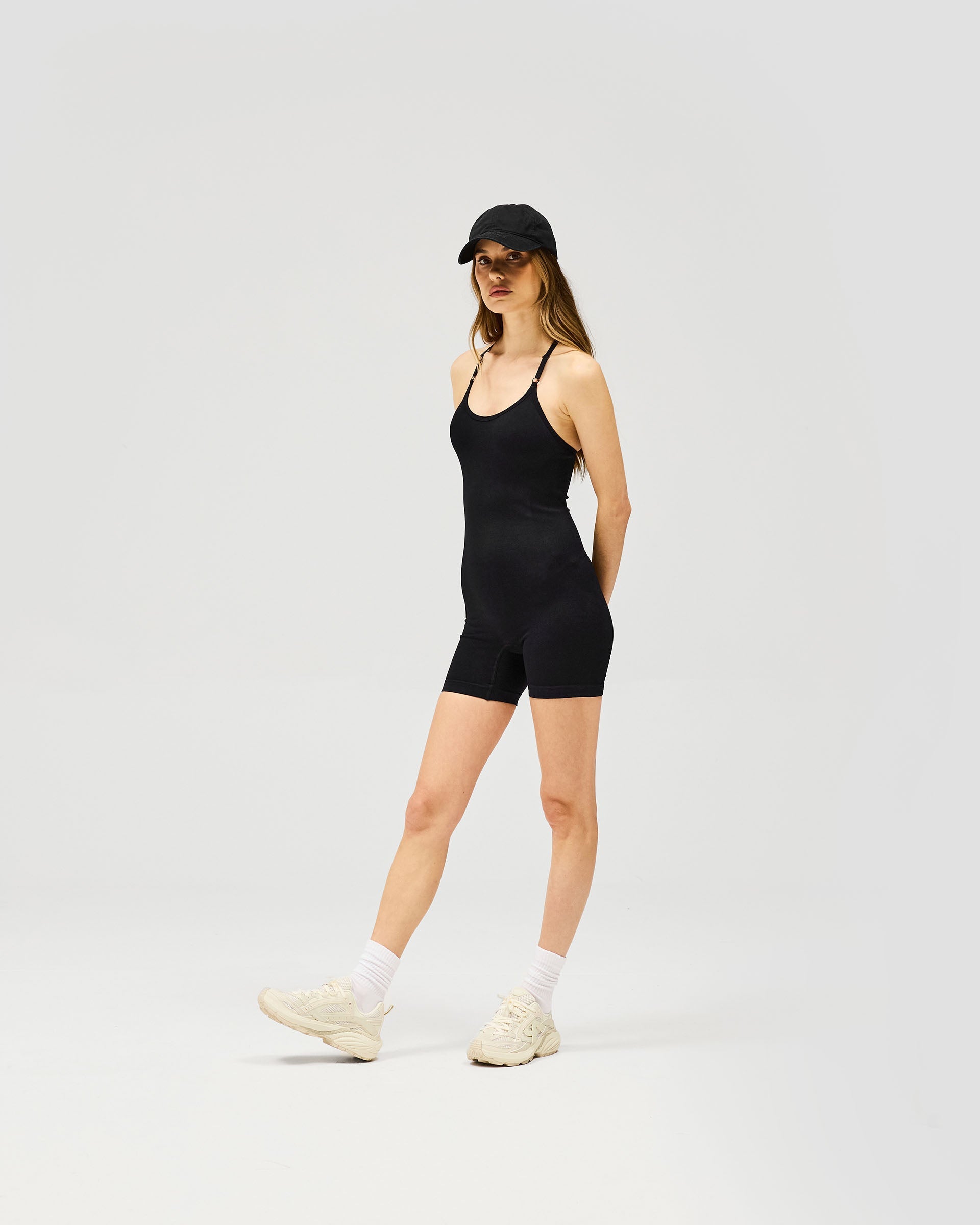 Woman wearing a black jumpsuit on a plain white background | Owners Club Seamless Jumpsuit in Jet Black | Jumpsuit with T-bar back and adjustable bra straps | Womens Owners Club Jumpsuits | Represent Clo