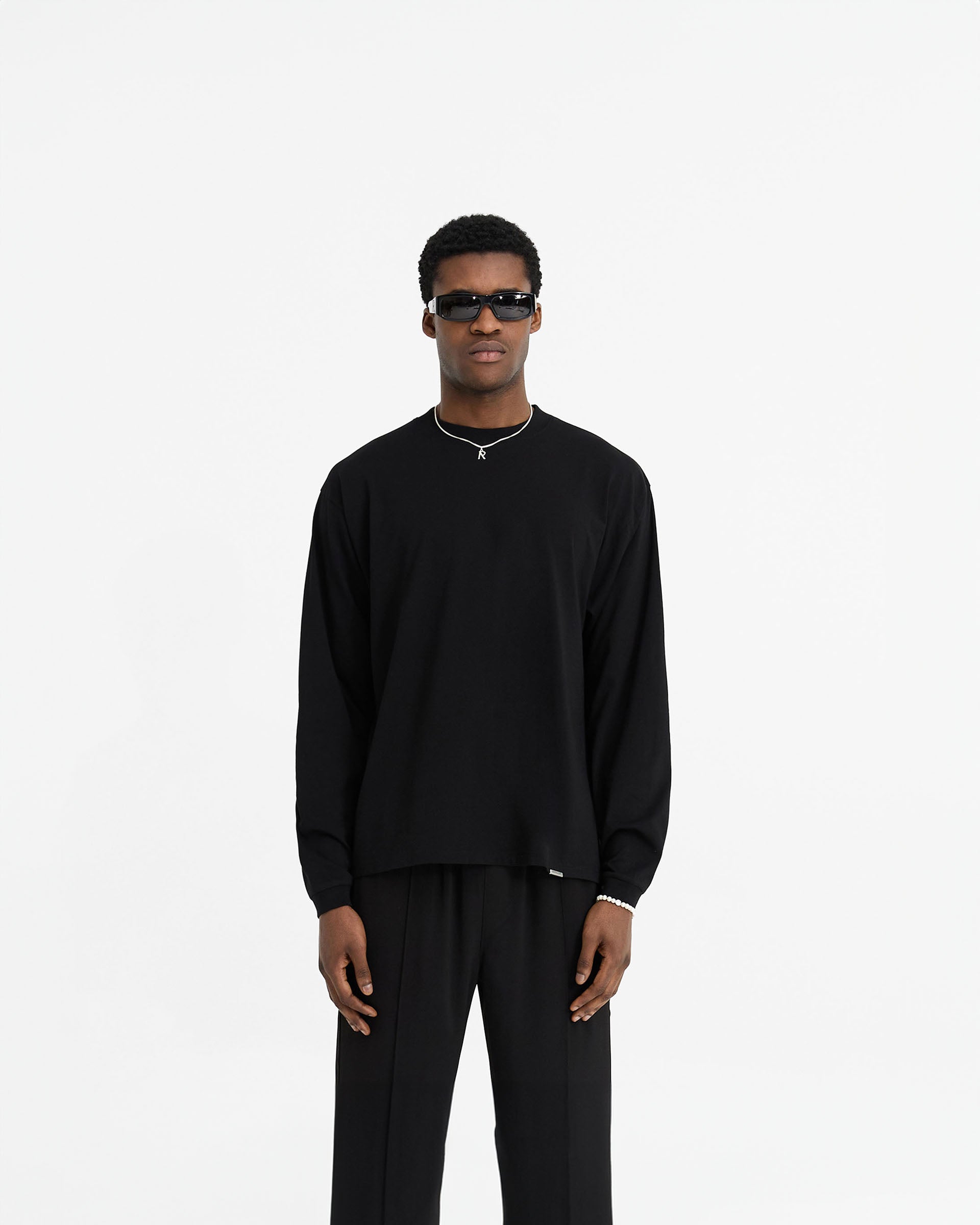 Man wearing a black long sleeve t-shirt on a plain white background | Initial Long Sleeve T-Shirt in Black | Regular fit long sleeve t-shirt with ribbed collar and cuffs | Initial T-Shirts | Represent Clo