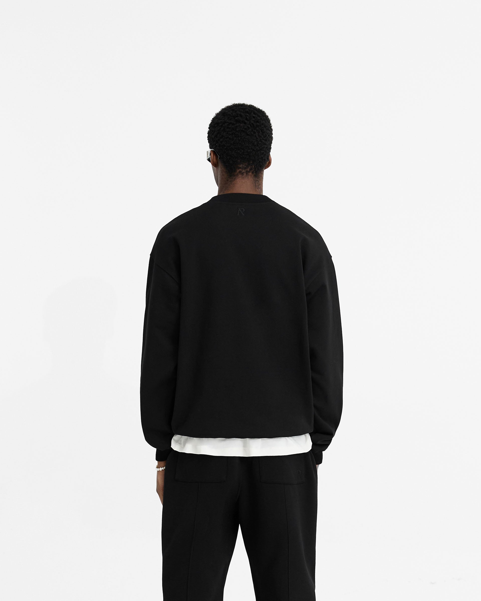 Man wearing a black oversized sweater on a plain white background | Initial Oversized Sweater in Black | Heavyweight loopback jersey organic cotton sweater | Initial Sweaters | Represent Clo