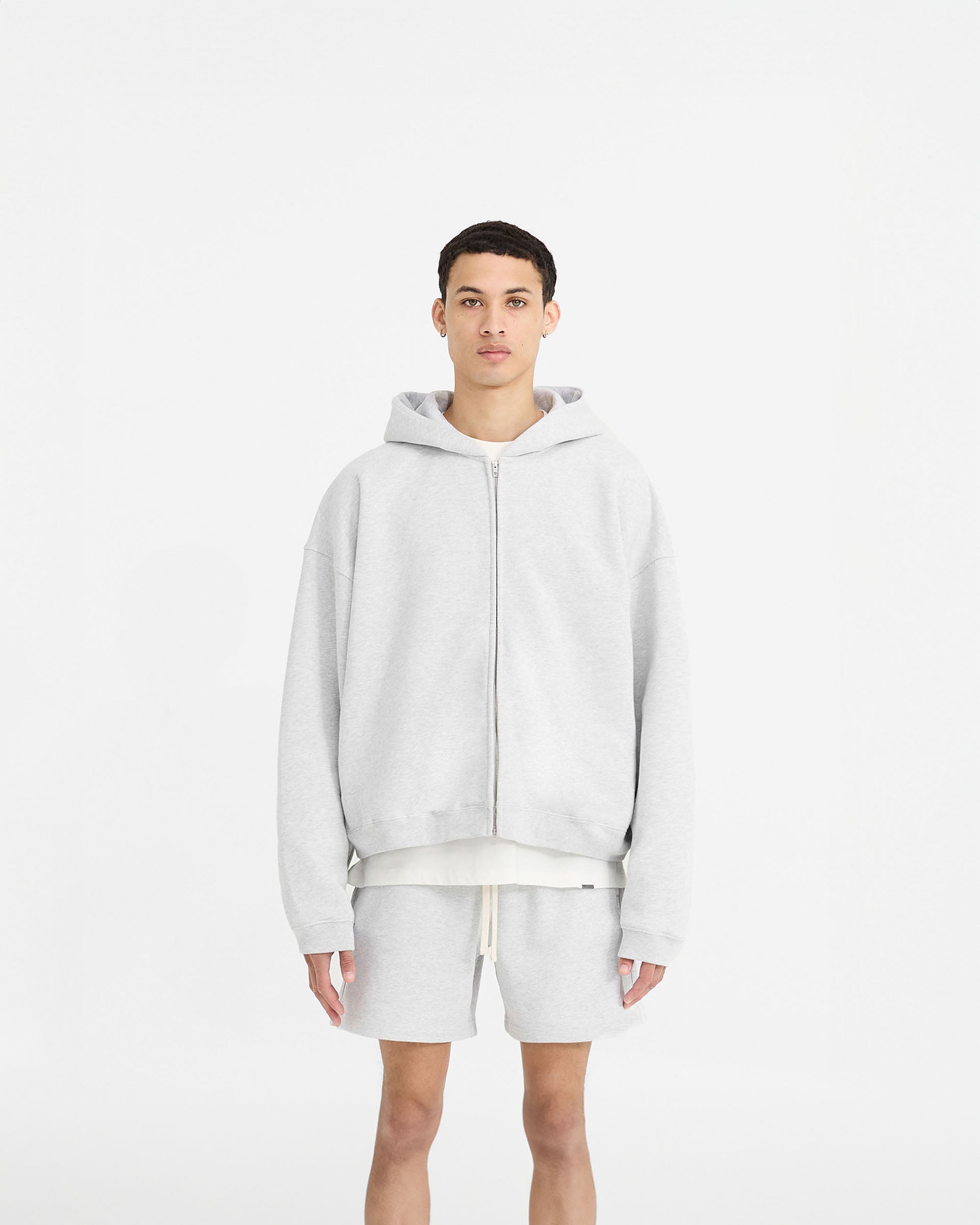 Man wearing a grey zip hoodie on a plain white background | Initial Boxy Zip Through Hoodie in Ice Grey Marl | Oversized boxy fit cropped zip hoodie | Initial Hoodies | Represent Clo