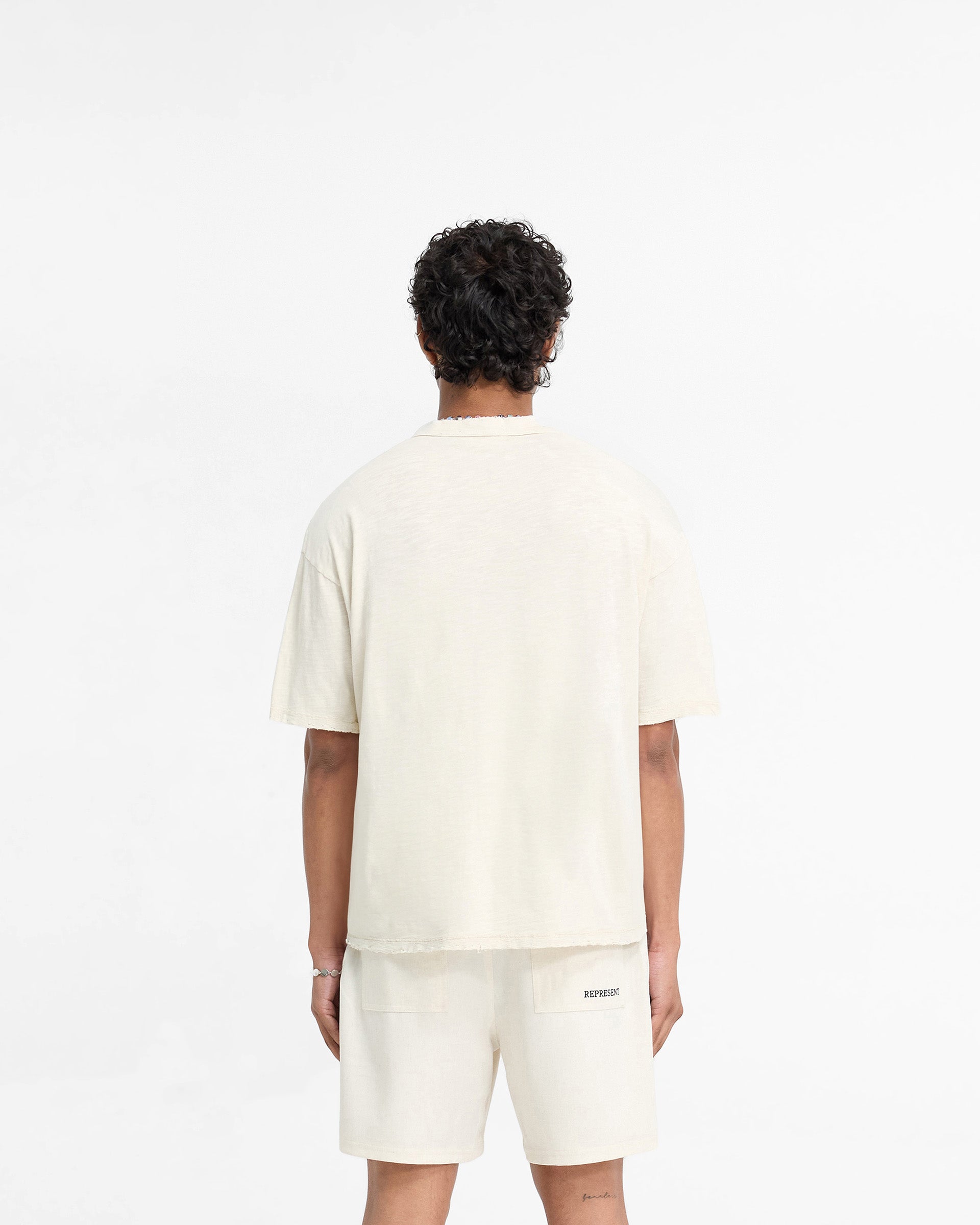 Man wearing a white t-shirt on a plain white background | Slub T-Shirt in Flat White | Oversized t-shirt with tonal embroidered branding | FW24 T-Shirts | Represent Clo