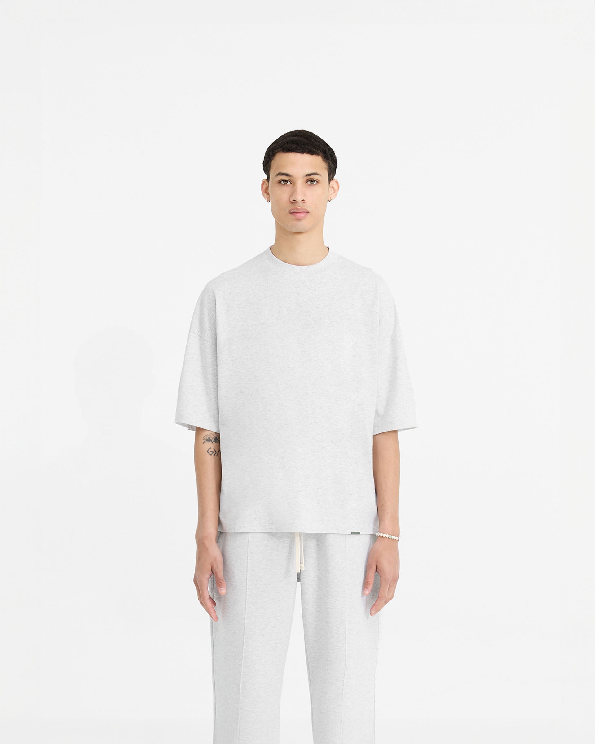 Man wearing a grey t-shirt on a plain white background | Initial Boxy T-Shirt in Ice Grey Marl | Oversized boxy cropped t-shirt with ribbed collar | Initial T-Shirts | Represent Clo