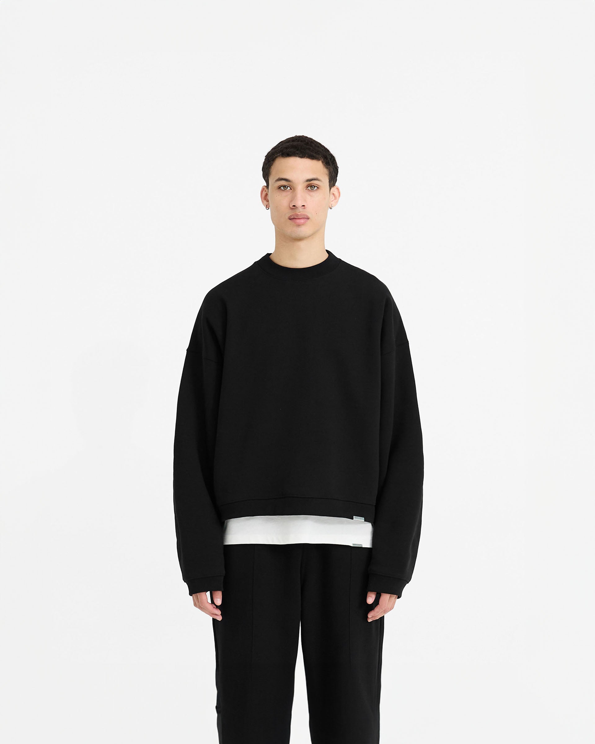 Man wearing a black sweater on a plain white background | Initial Boxy Sweater in Black | Oversized boxy sweater with cropped body length | Initial Sweaters | Represent Clo