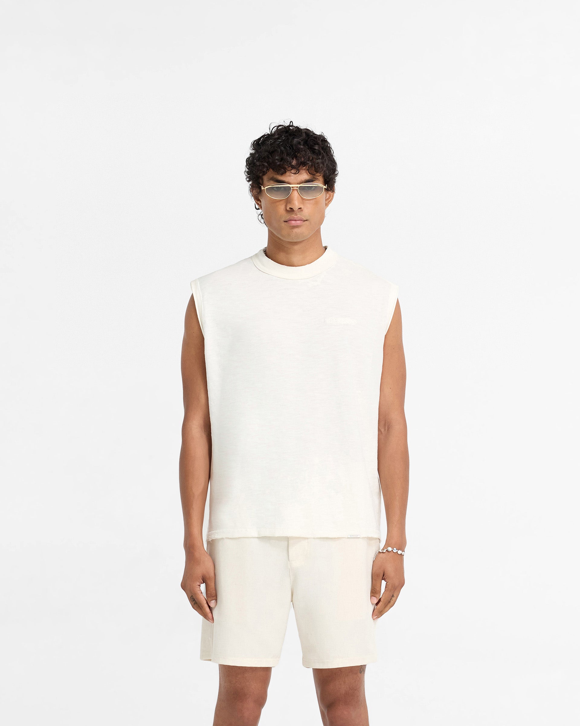 Man wearing a white tank top on a plain white background | Slub Tank in Flat White | Oversized tank top with tonal embroidery and distressed details | FW24 T-Shirts | Represent Clo