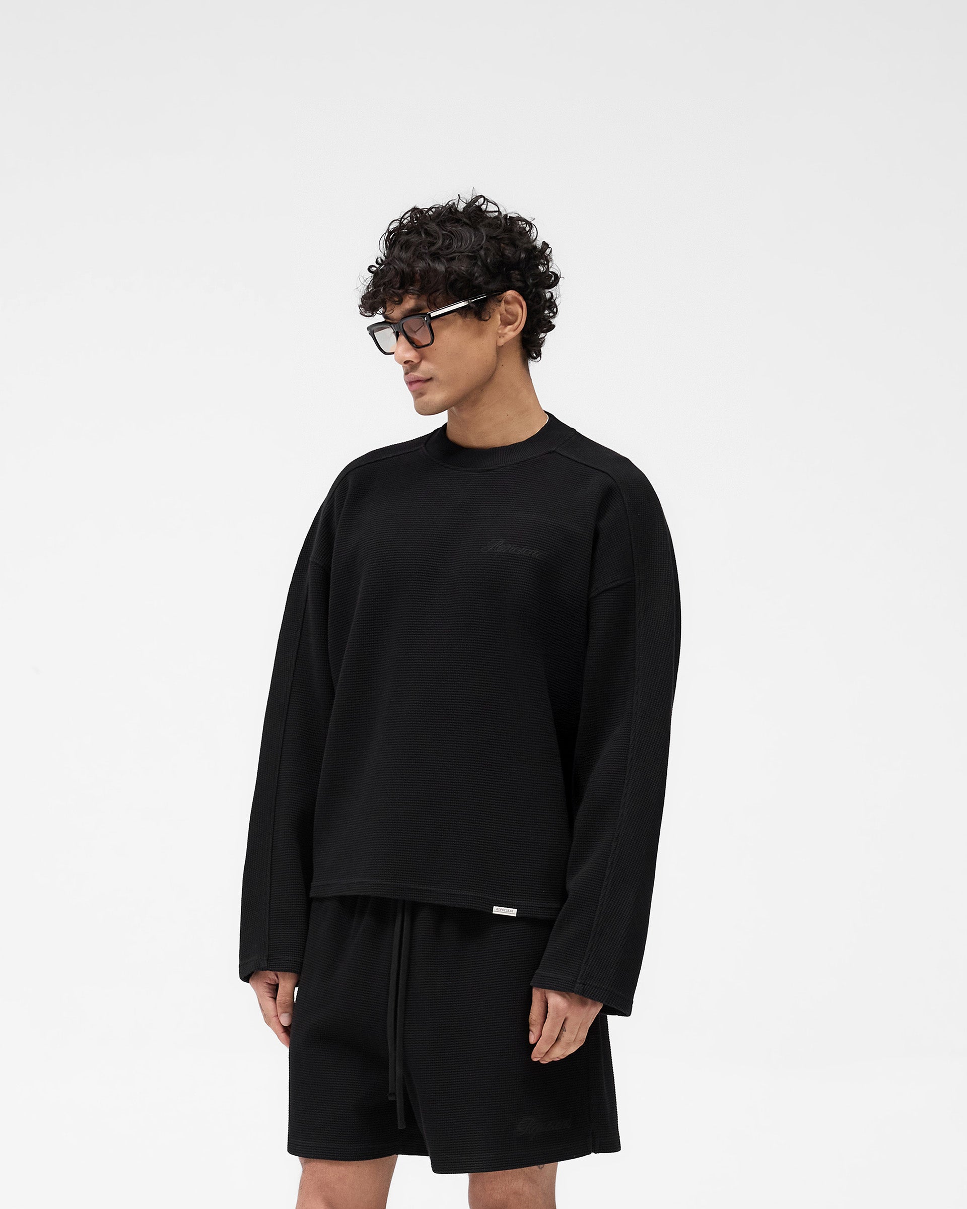 Back product image of a mens black waffle long sleeve t-shirt on a plain white background | Waffle Long Sleeve T-Shirt in Black | Long sleeve t-shirt with boxy fit and cover stitch detailing | SS25 T-Shirts | Represent Clo