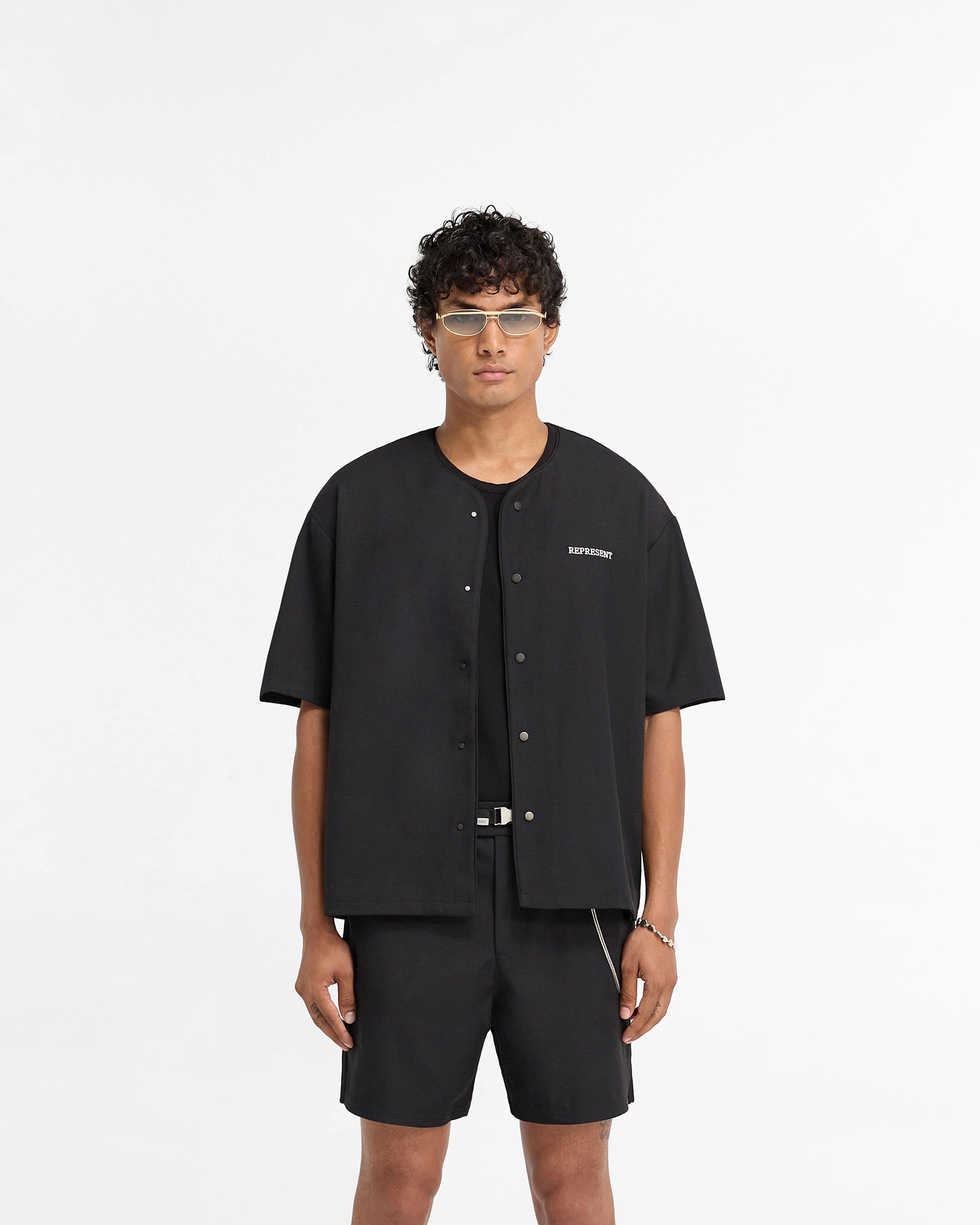 Man wearing a black shirt on a plain white background | Baseball Shirt in Black | Collarless baseball shirt with popper button up front | FW24 Shirts | Represent Clo