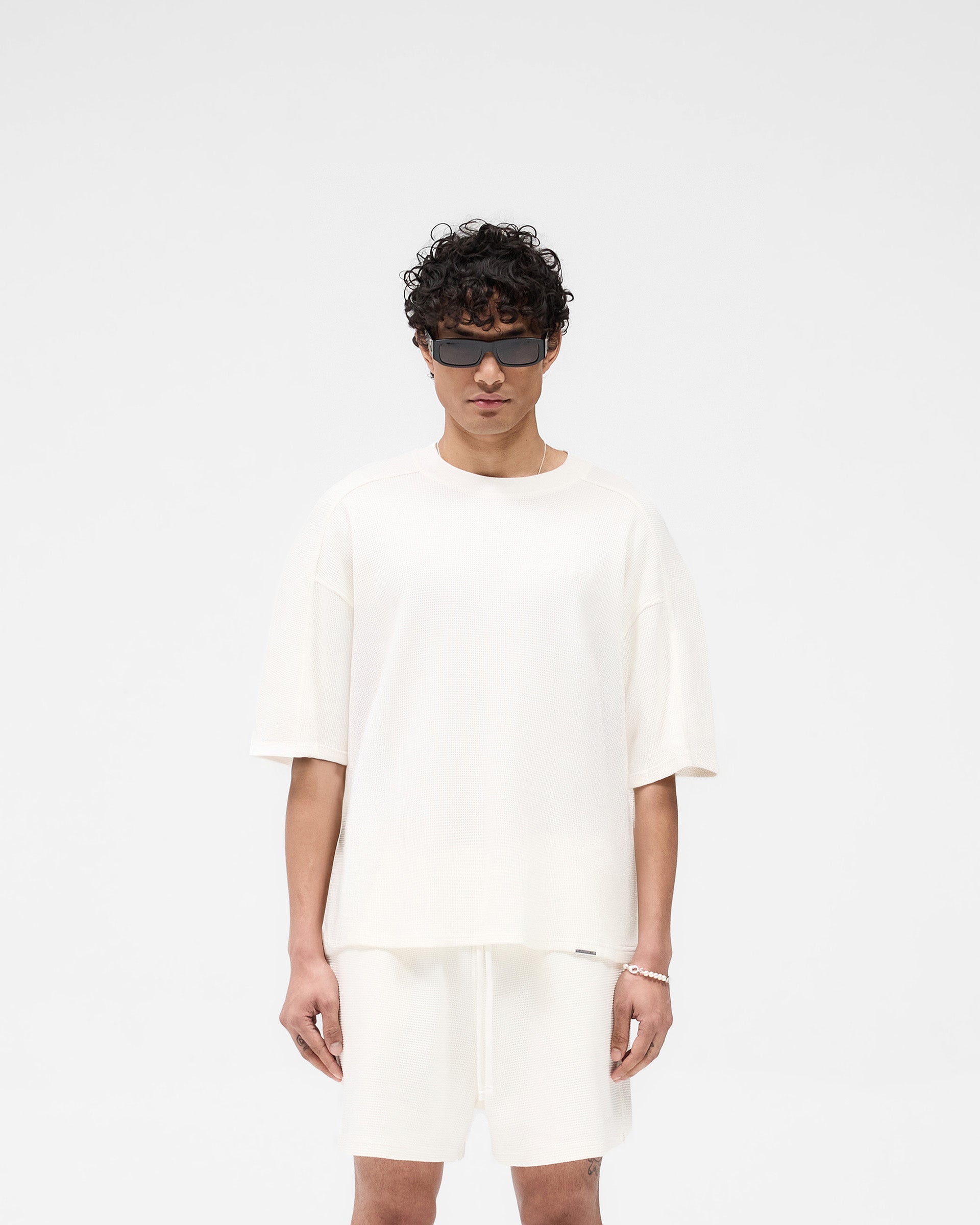 Man wearing a white t-shirt on a plain white background | Waffle T-Shirt in Flat White | Boxy fit t-shirt with interlock waffle fabric | SS25 T-Shirts | Represent Clo