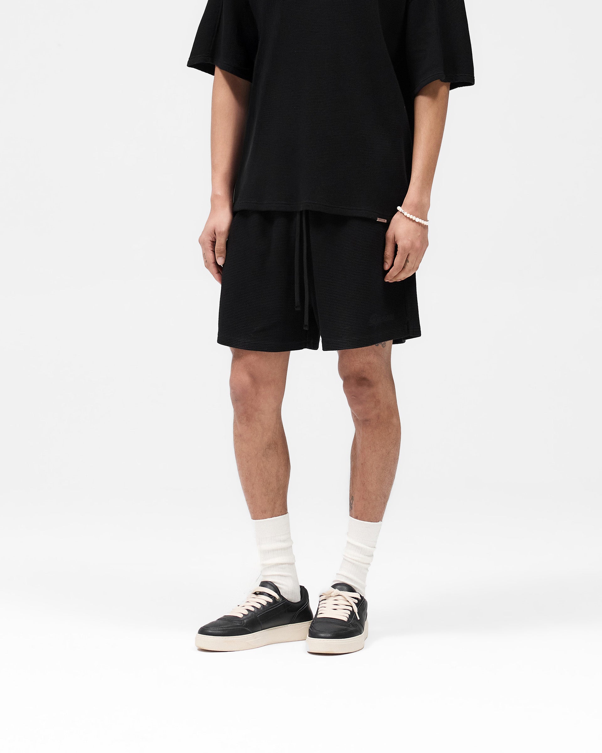 Back product image of mens black shorts on a plain white background | Waffle Shorts in Black | Elasticated waistband with adjustable drawstring | SS25 Shorts | Represent Clo