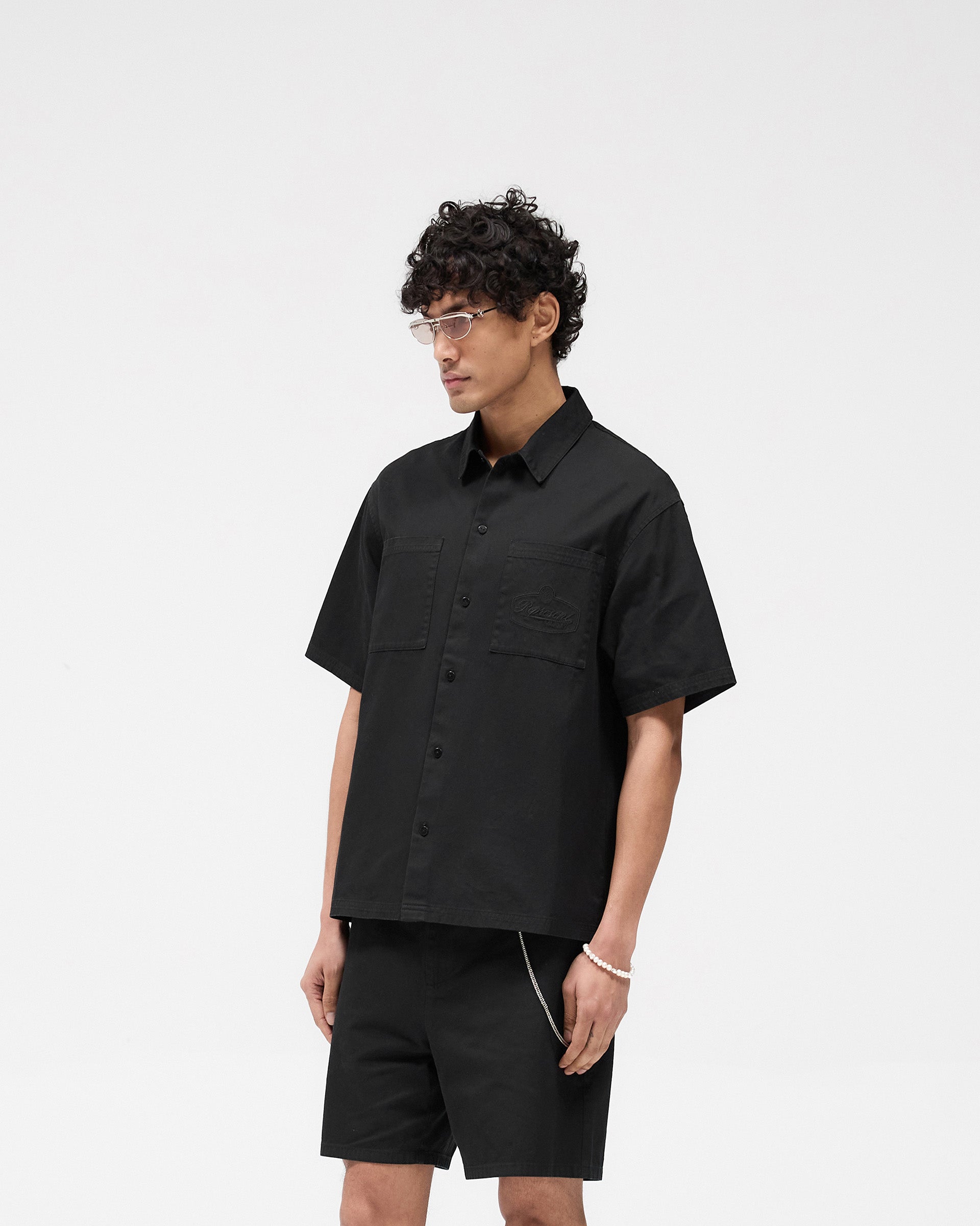 Back product image of a mens black shirt on a plain white background | Short Sleeve Cotton Overshirt in Washed Black | Overshirt with dual chest pockets | SS25 Shirts | Represent Clo