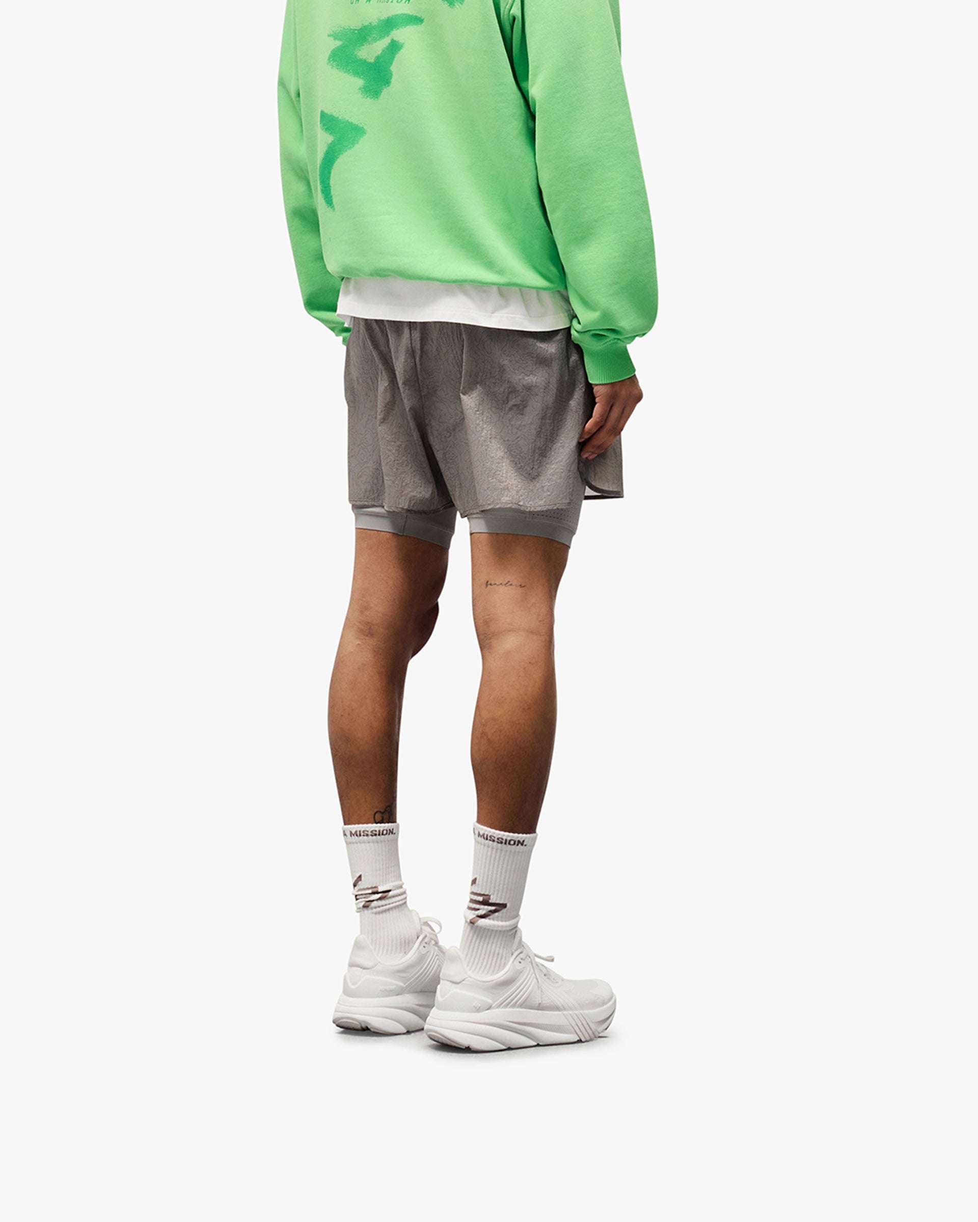 Man wearing grey 2-in-1 run shorts on a plain white background | 247 Contour 2-In-1 Run Shorts in Titanium | Shorts with inner legging and zip pockets | 247 Shorts | Represent Clo