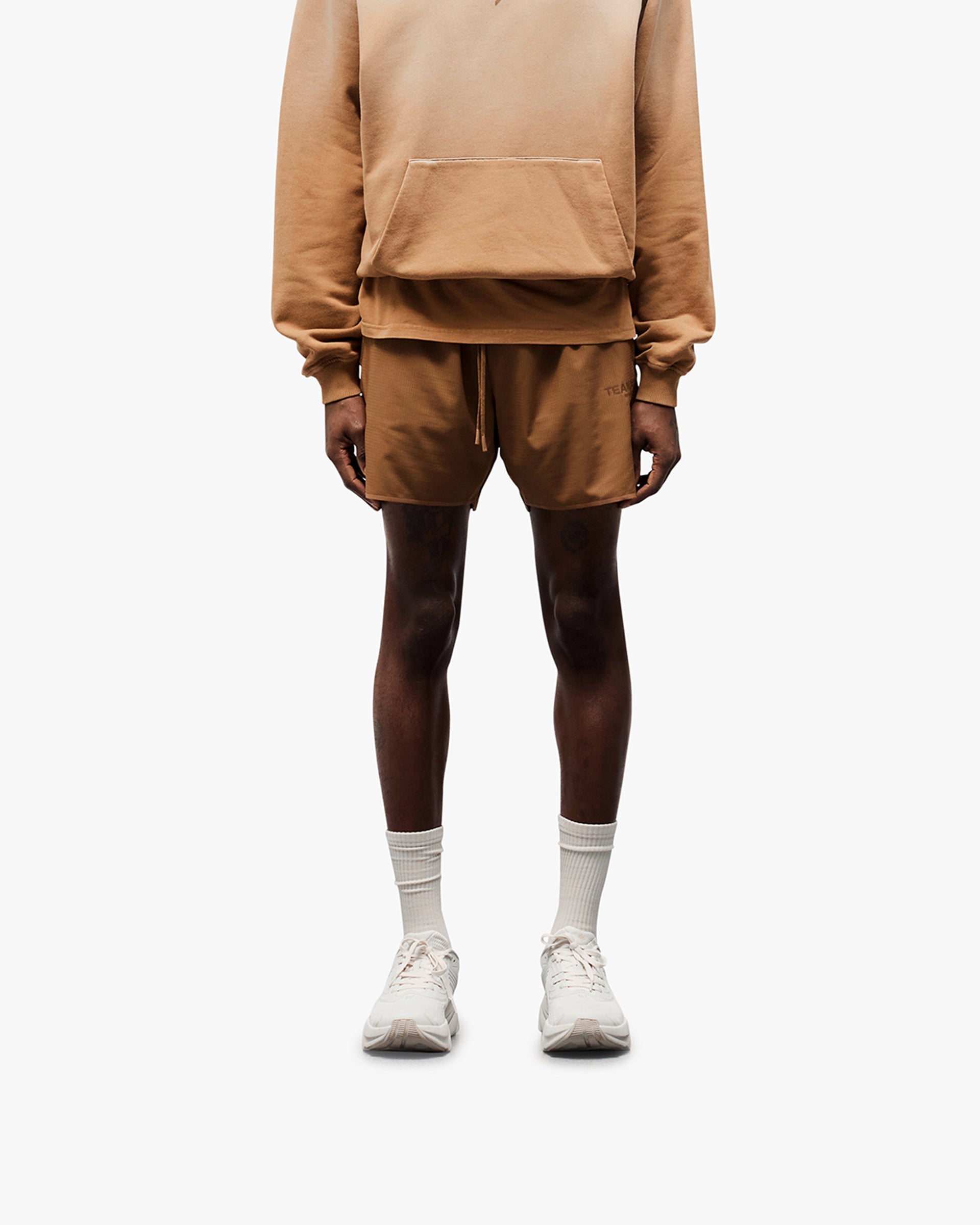 Man wearing rust shorts on a plain white background | Team 247 Aero Shorts in Rust | Shorts with branded waistband and zip pockets | 247 Shorts | Represent Clo