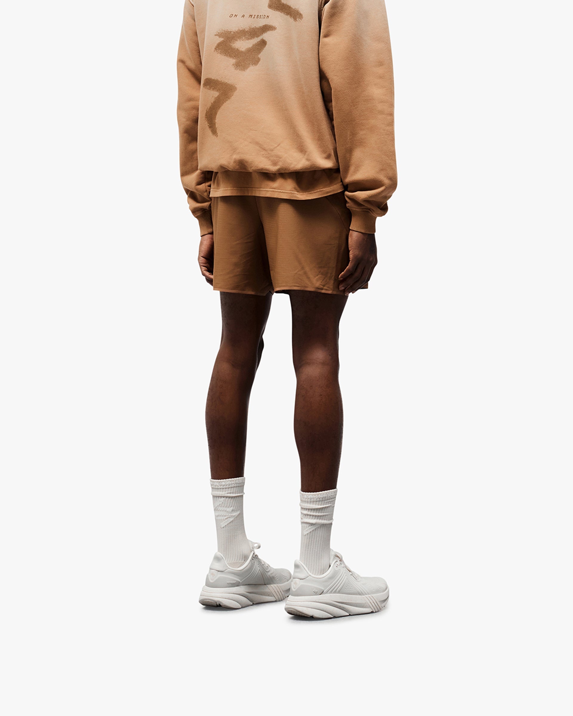 Man wearing rust shorts on a plain white background | Team 247 Aero Shorts in Rust | Running shorts with branded waistband and zip pockets | 247 Shorts | Represent Clo