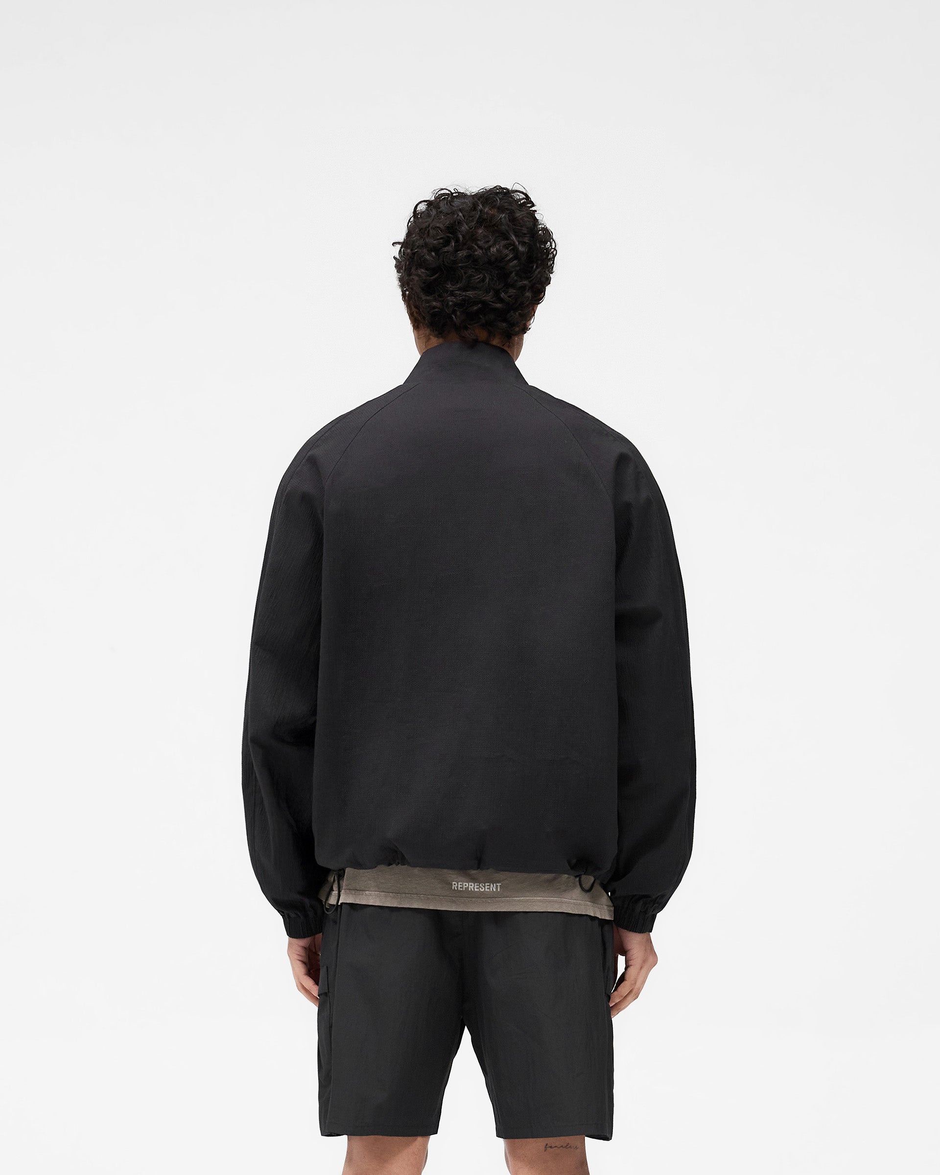 Man wearing a black jacket on a plain white background | Quarter Zip Jacket in Black | Outerwear with a quarter zip and oversized silhouette | SS25 Outerwear | Represent Clo