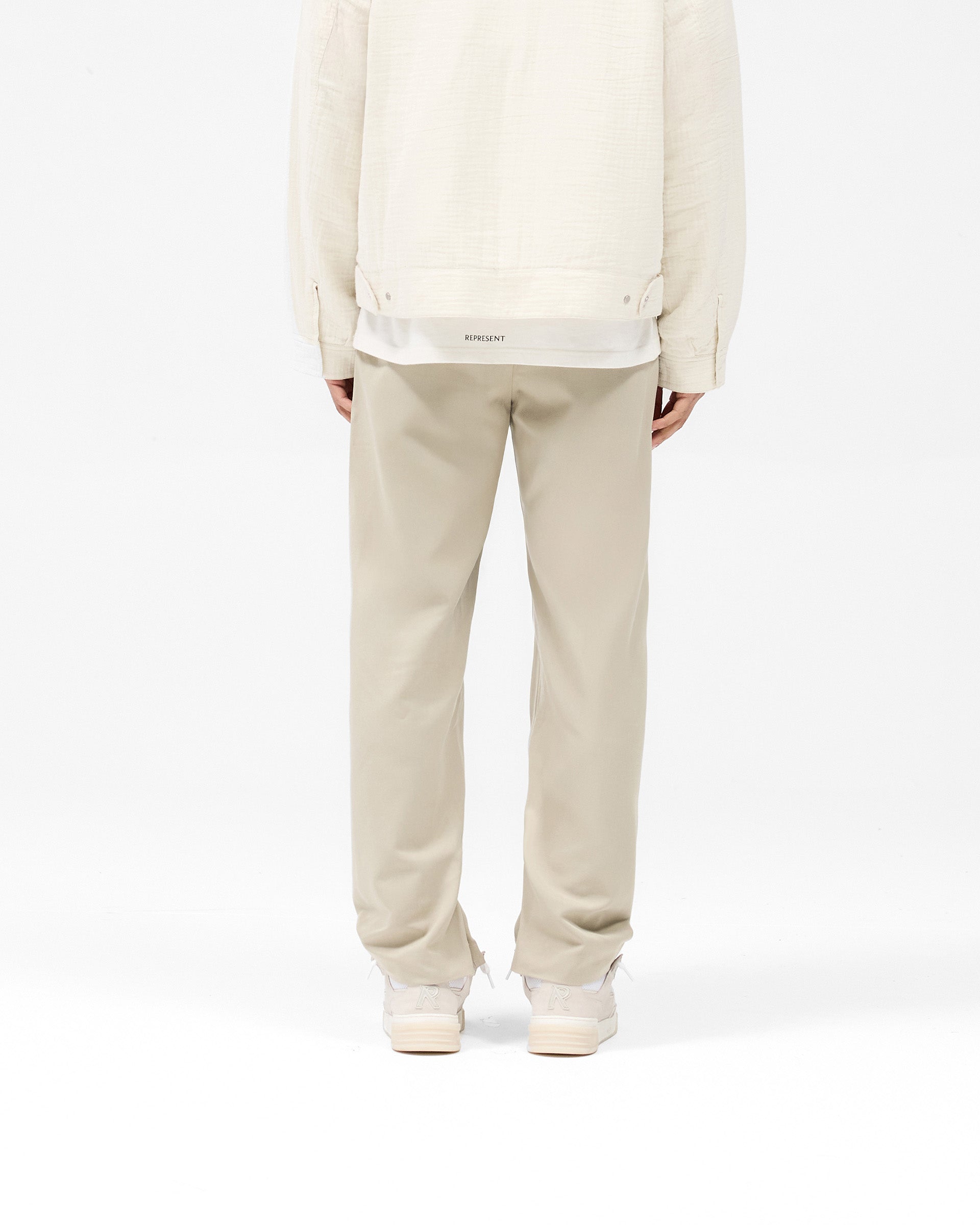 Man wearing light grey pants on a plain white background | Core Pant in Light Grey | Pants with hybrid-style waistband and straight-leg silhouette | SS25 Pants | Represent Clo