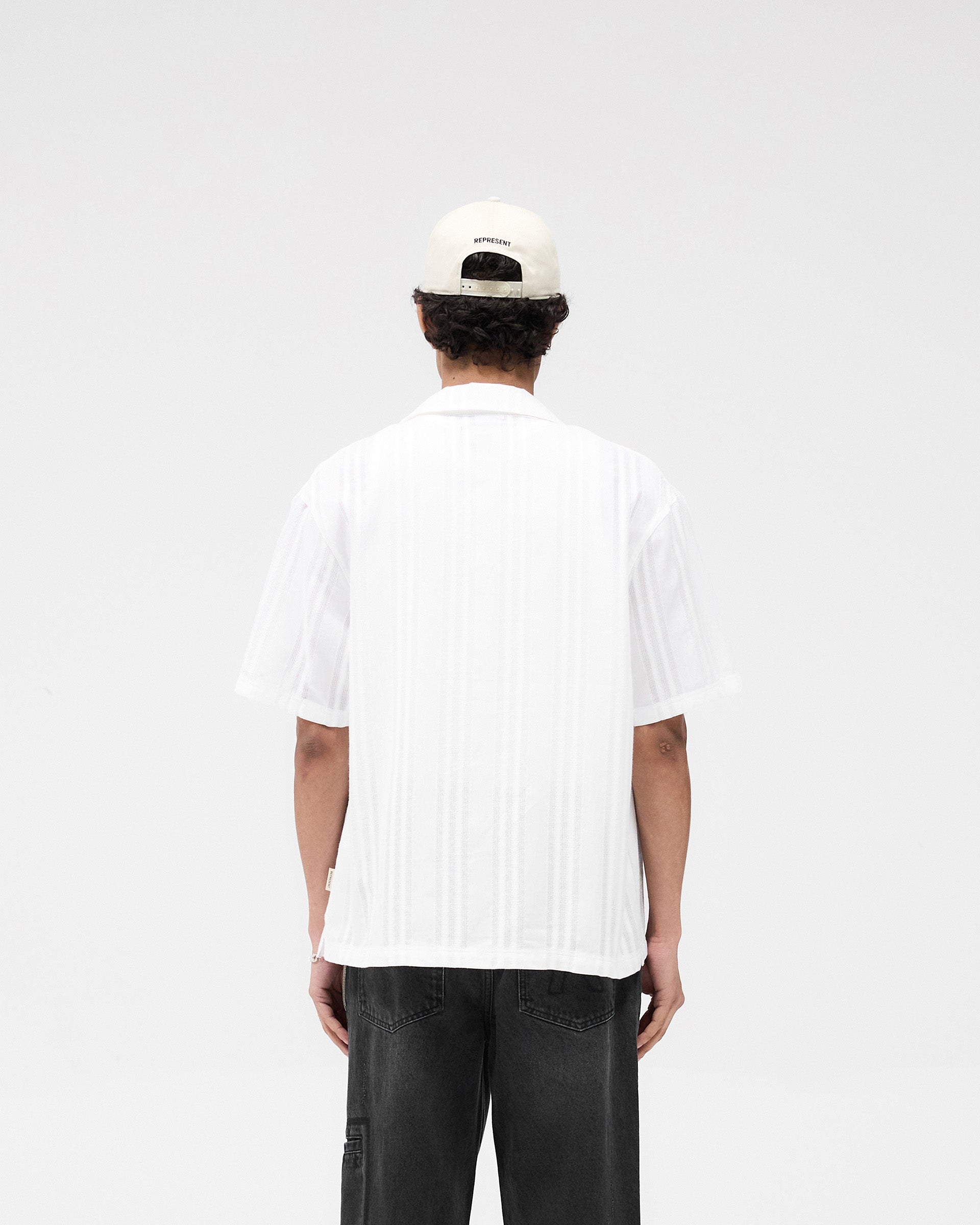Man wearing a white embroidered bowling shirt on a plain white background | Embroidered Bowling Shirt in Antique White | Lightweight relaxed fit bowling shirt | SS25 Shirts | Represent Clo