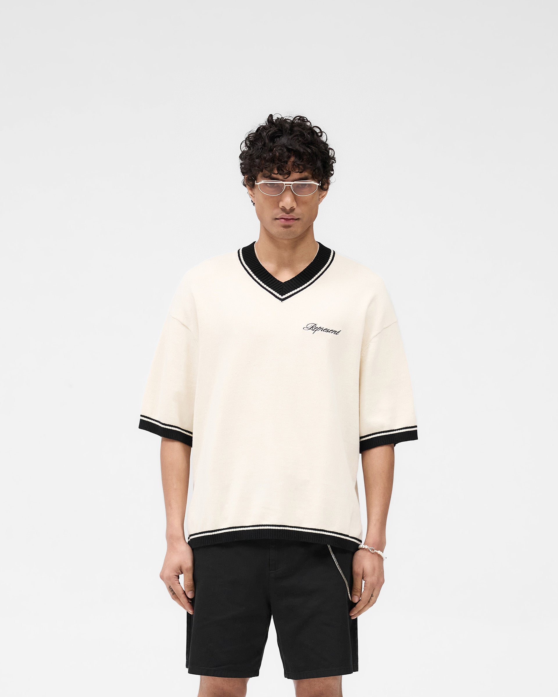 Man wearing an off white knit on a plain white background | Script Embroidered Knit in Off White | Knitwear with a bold v-neckline and ribbed detailing | SS25 Knitwear | Represent Clo